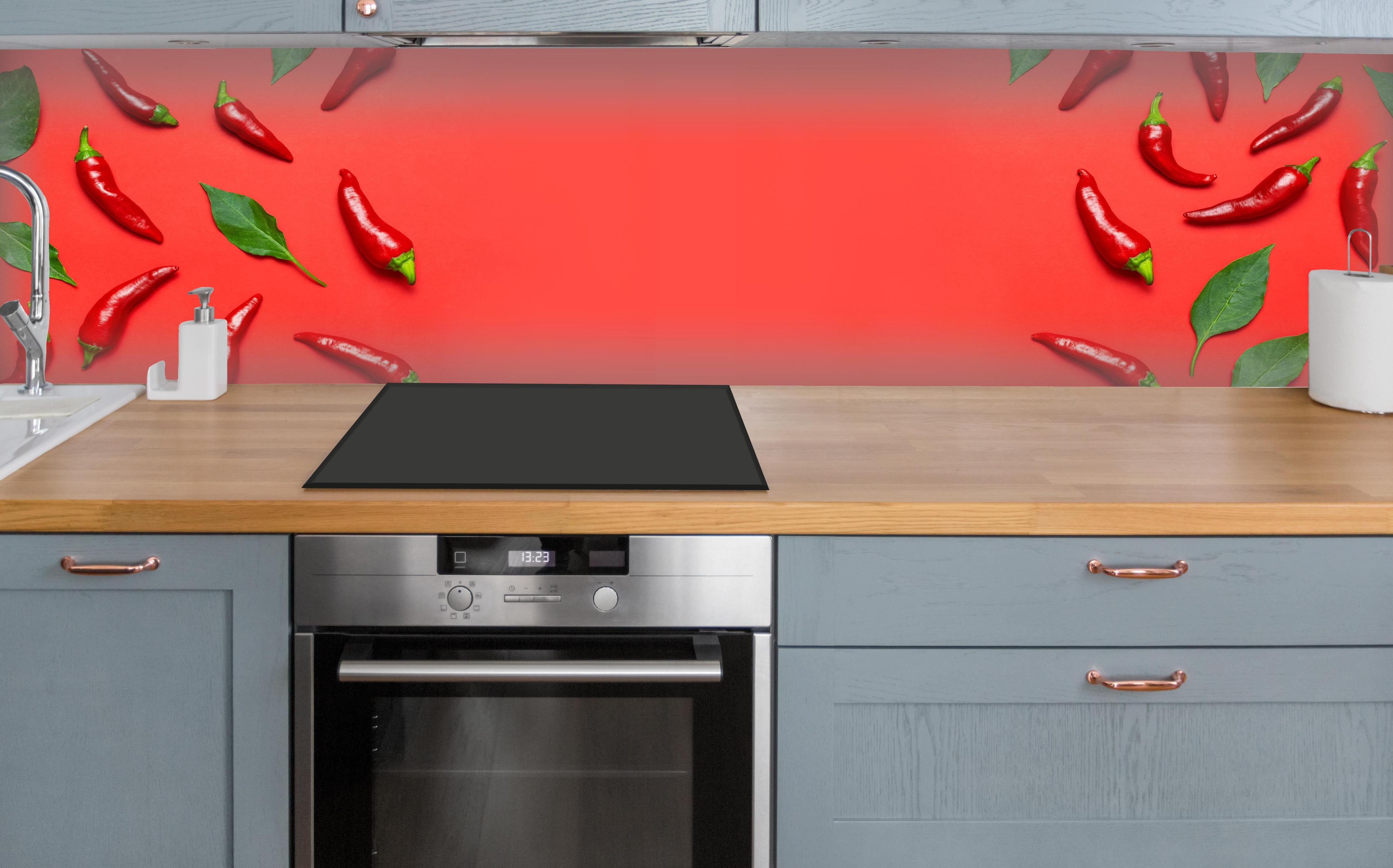Küche - Rote Chili mit grünen Blättern über polierter Holzarbeitsplatte mit Cerankochfeld