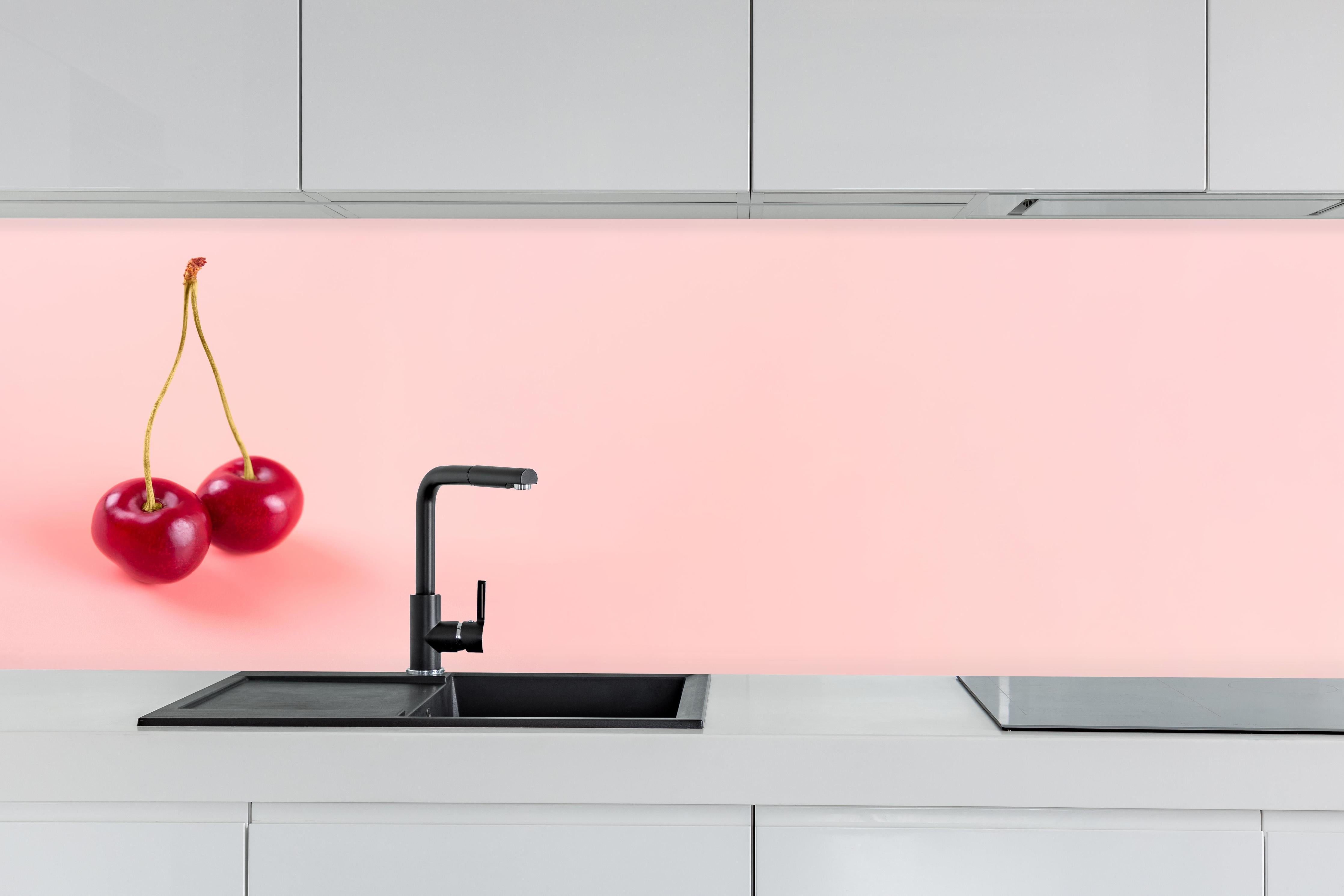 Küche - Rote Kirschen auf Rosa Hintergrund hinter weißen Hochglanz-Küchenregalen und schwarzem Wasserhahn