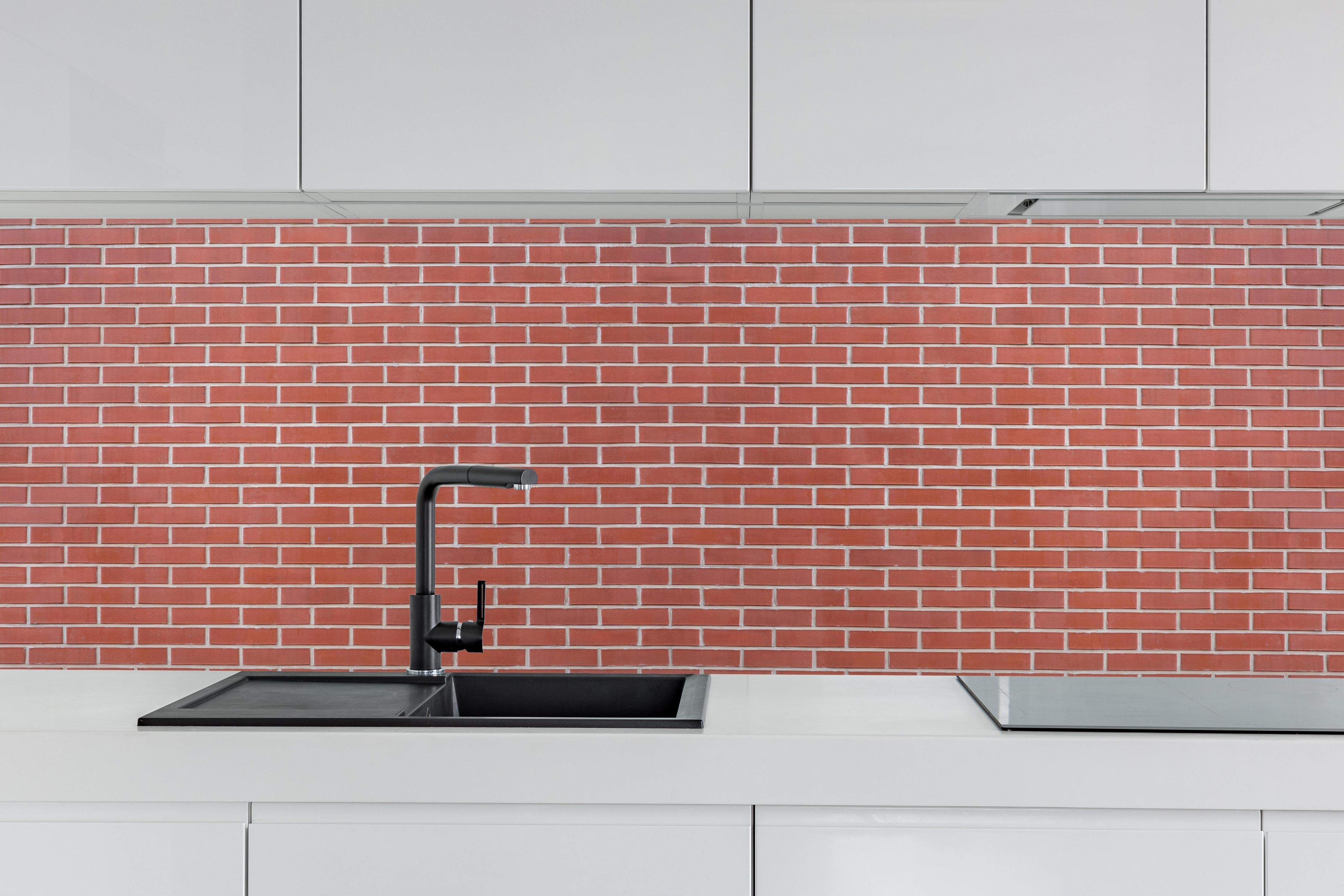 Küche - Rote Ziegelstein-Textur hinter weißen Hochglanz-Küchenregalen und schwarzem Wasserhahn