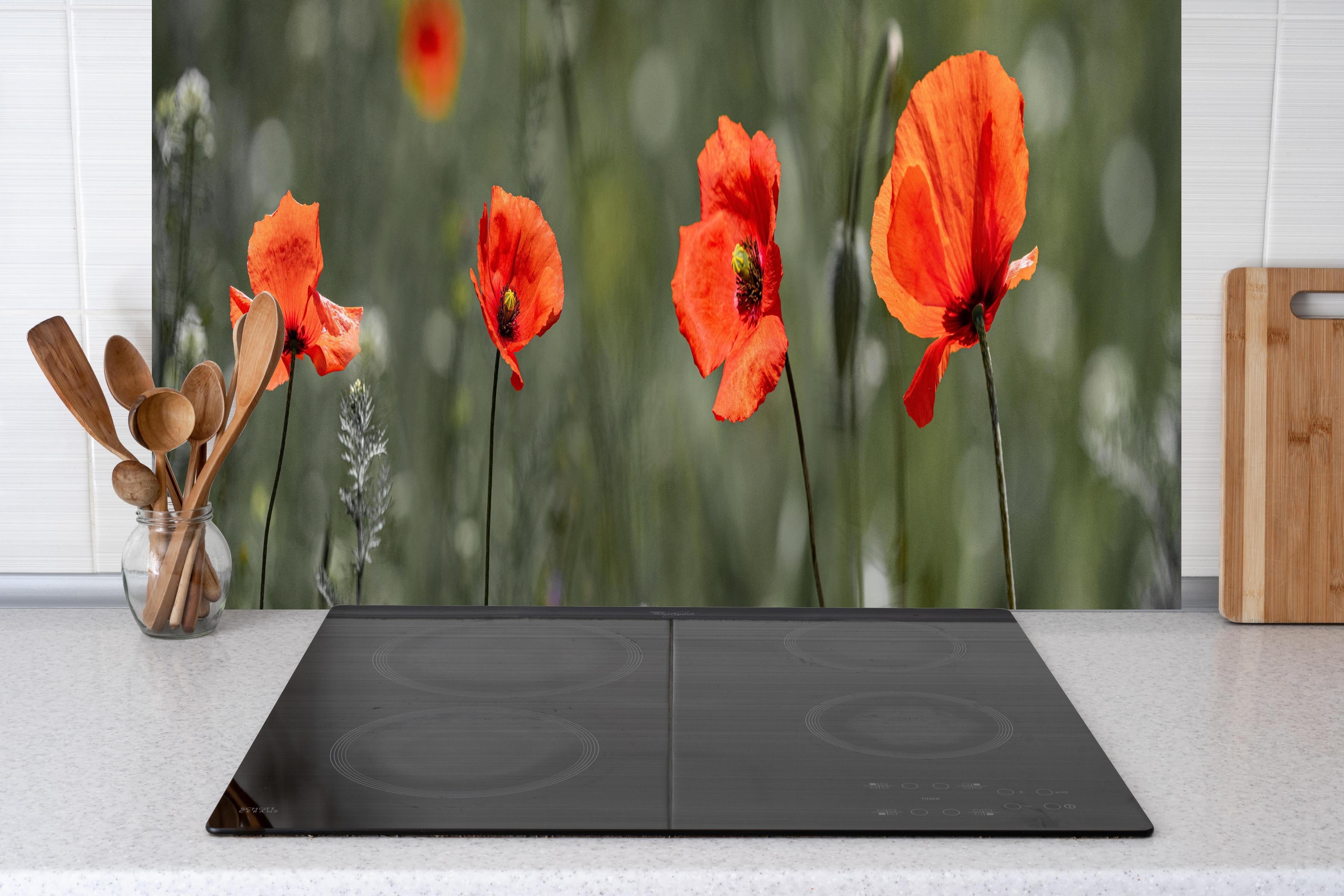Küche - Roter Mohn inmitten des Grüns hinter Cerankochfeld und Holz-Kochutensilien