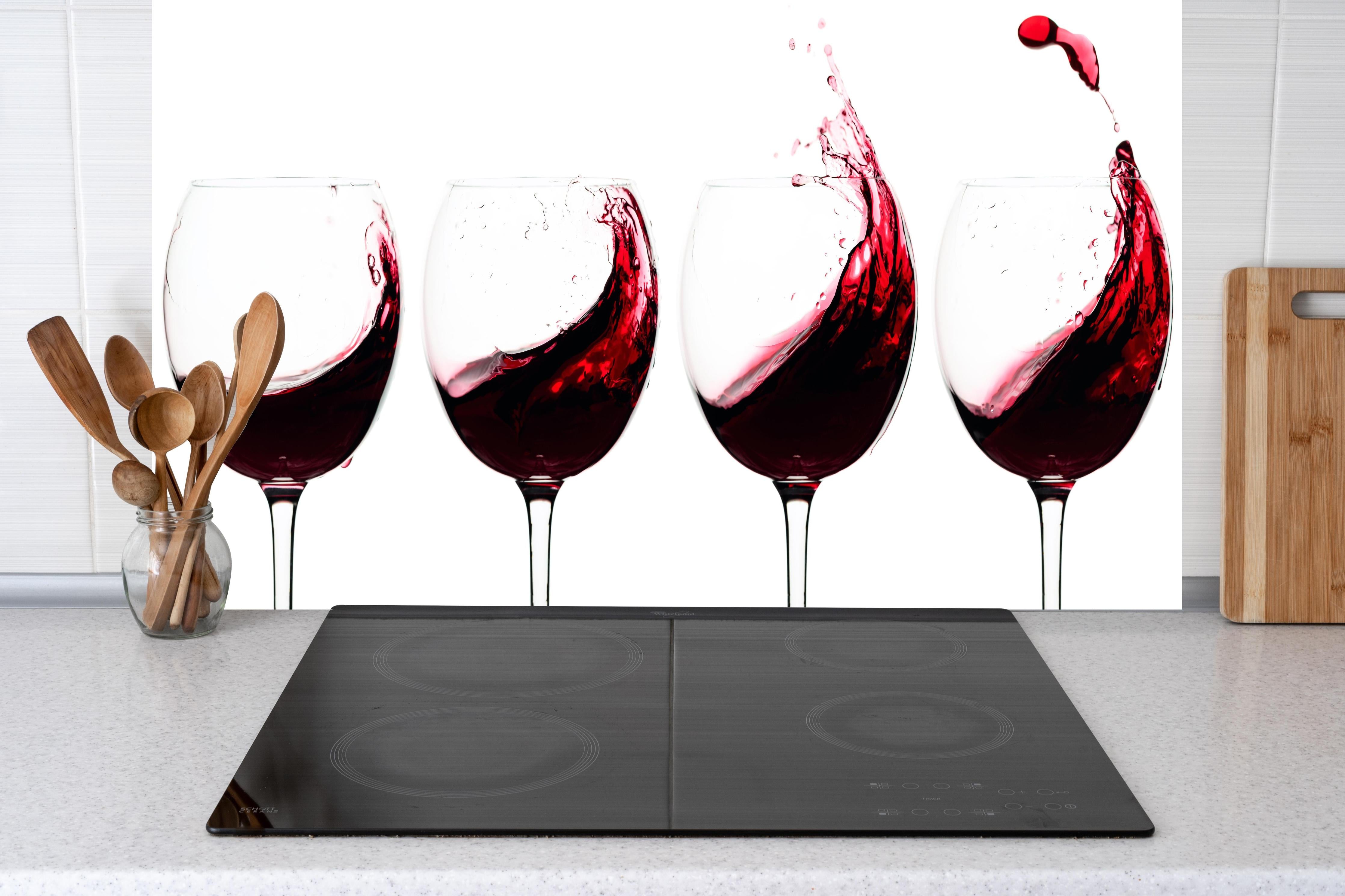 Küche - Rotwein-Splash in Weingläsern hinter Cerankochfeld und Holz-Kochutensilien