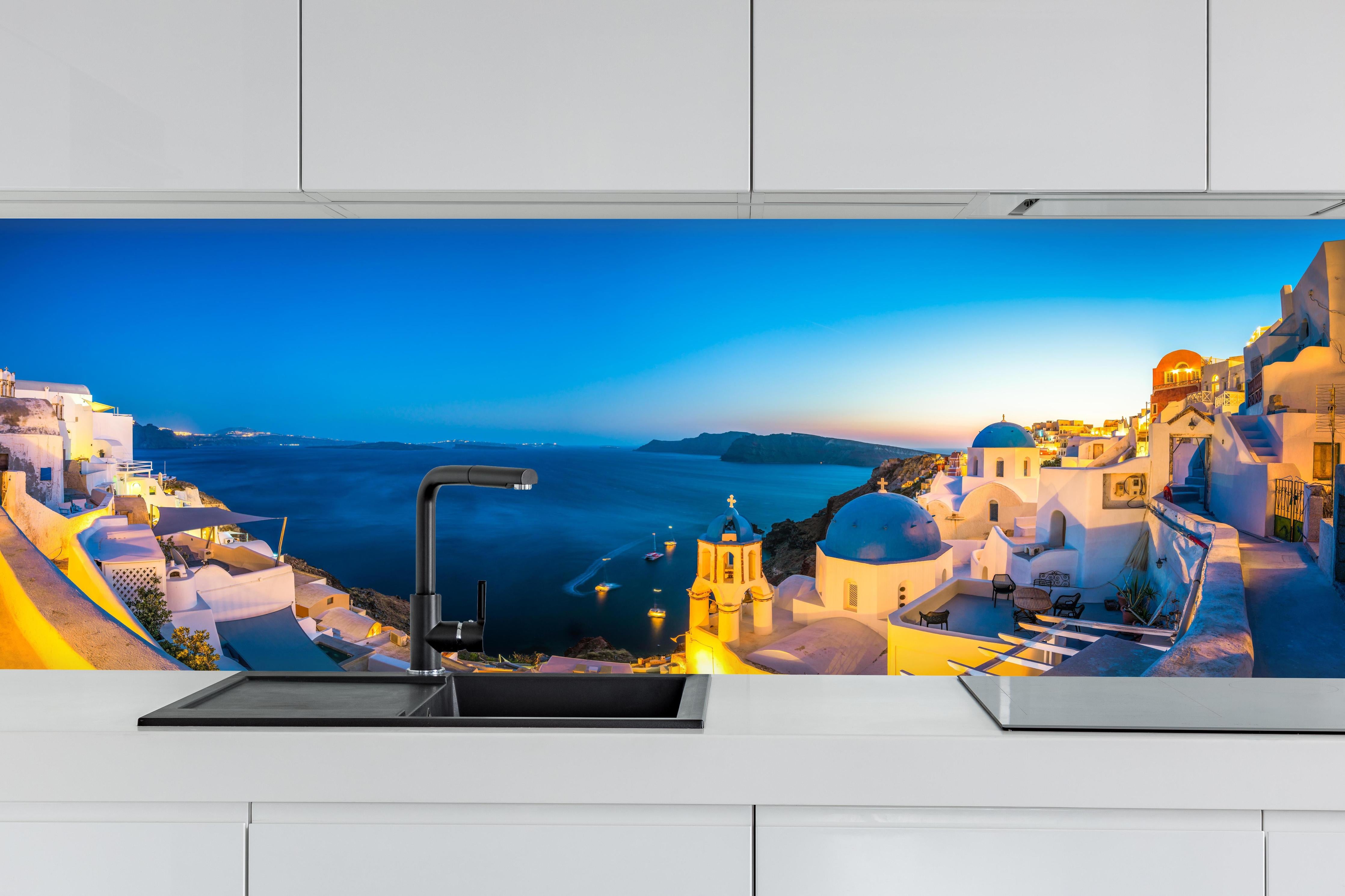 Küche - Santorini Blau-Weiß Panorama hinter weißen Hochglanz-Küchenregalen und schwarzem Wasserhahn