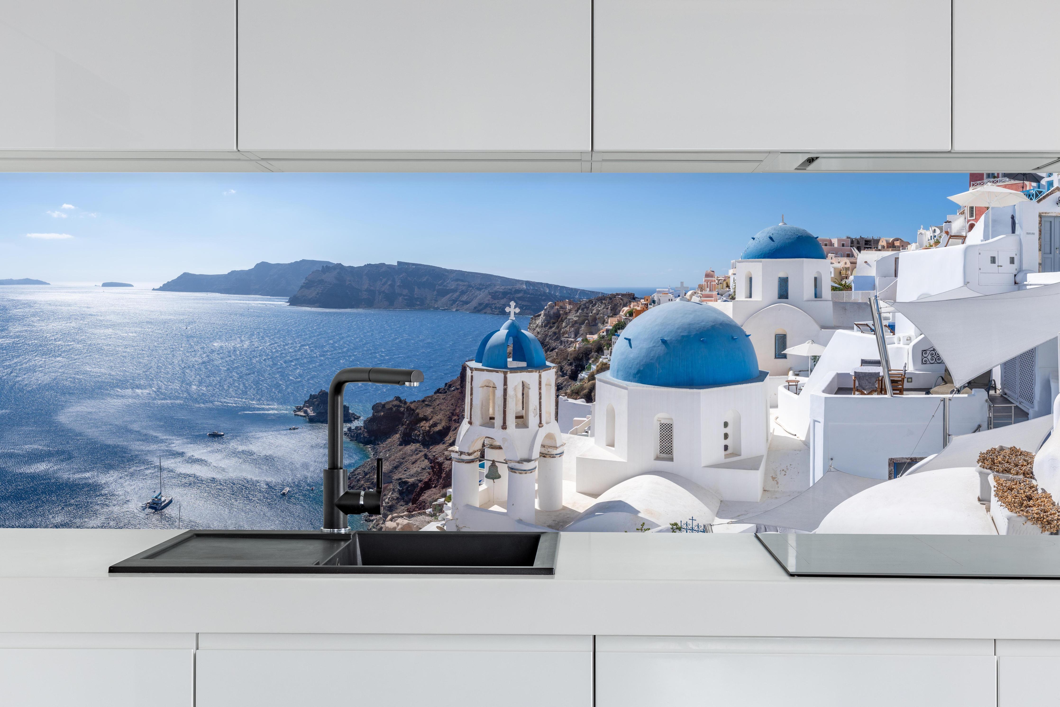 Küche - Santorini Blau-Weiß Skyline hinter weißen Hochglanz-Küchenregalen und schwarzem Wasserhahn