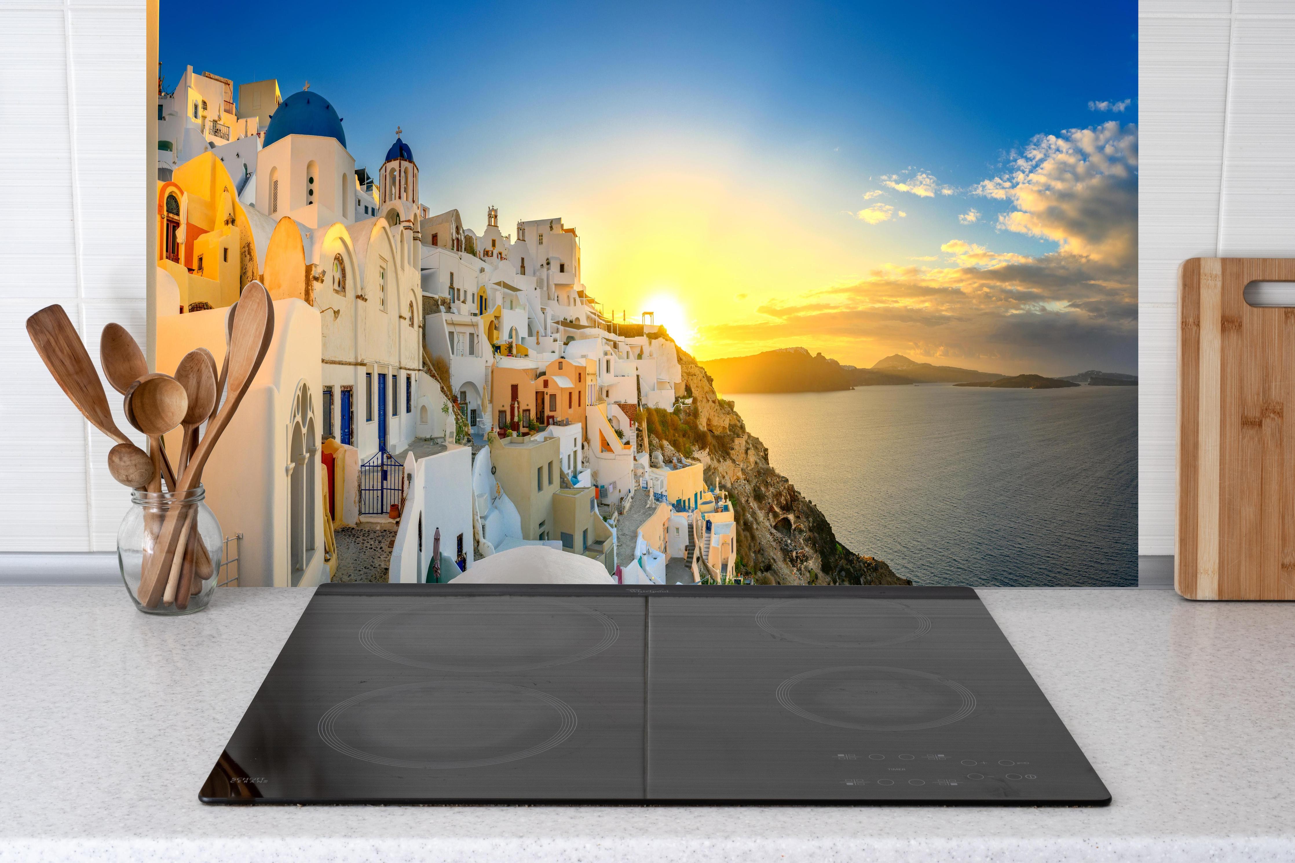 Küche - Santorini Sonnenuntergang Skyline hinter Cerankochfeld und Holz-Kochutensilien