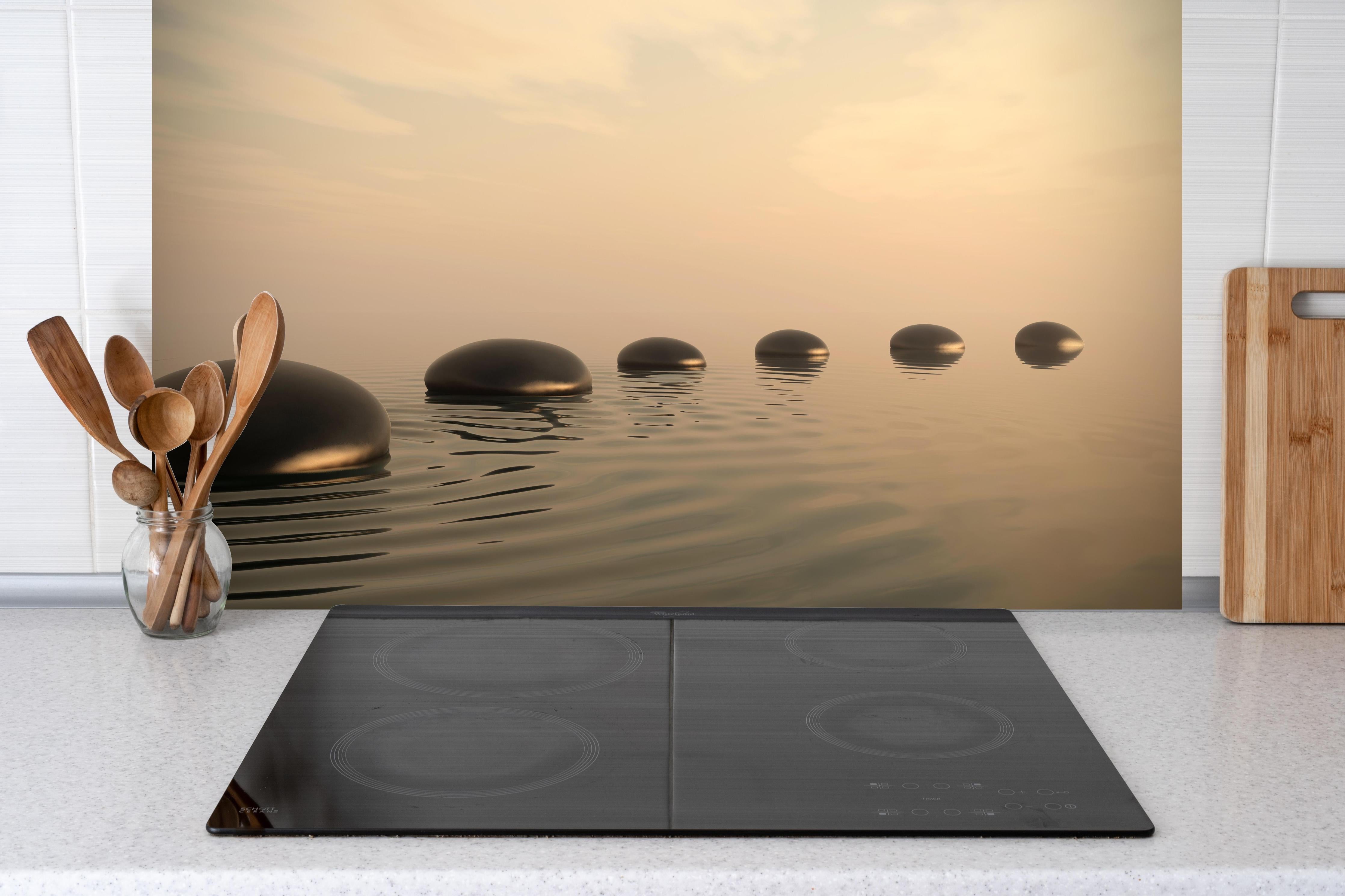 Küche - Schwarze Zen-Steine auf ruhigem Beige hinter Cerankochfeld und Holz-Kochutensilien