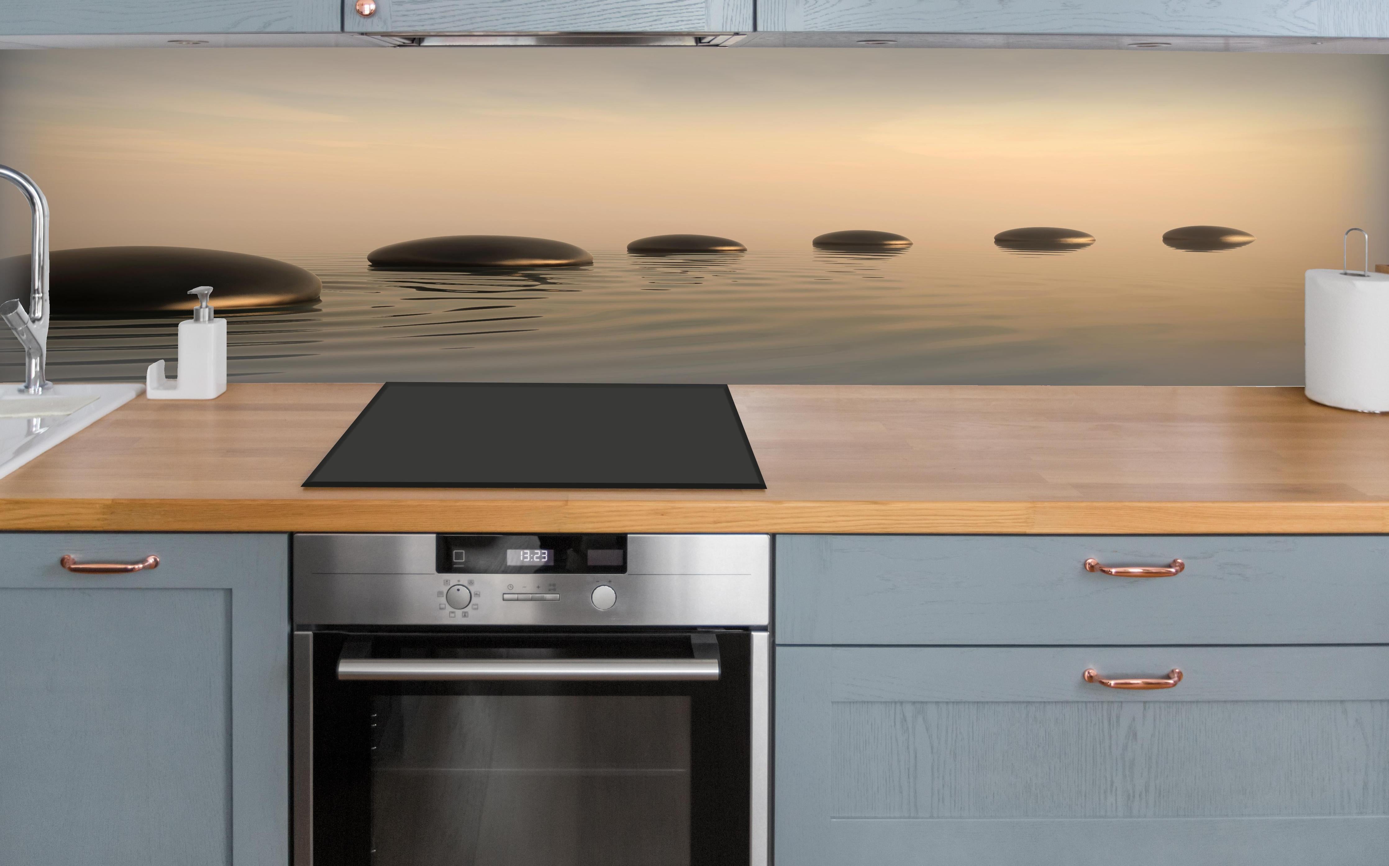 Küche - Schwarze Zen-Steine auf ruhigem Beige über polierter Holzarbeitsplatte mit Cerankochfeld