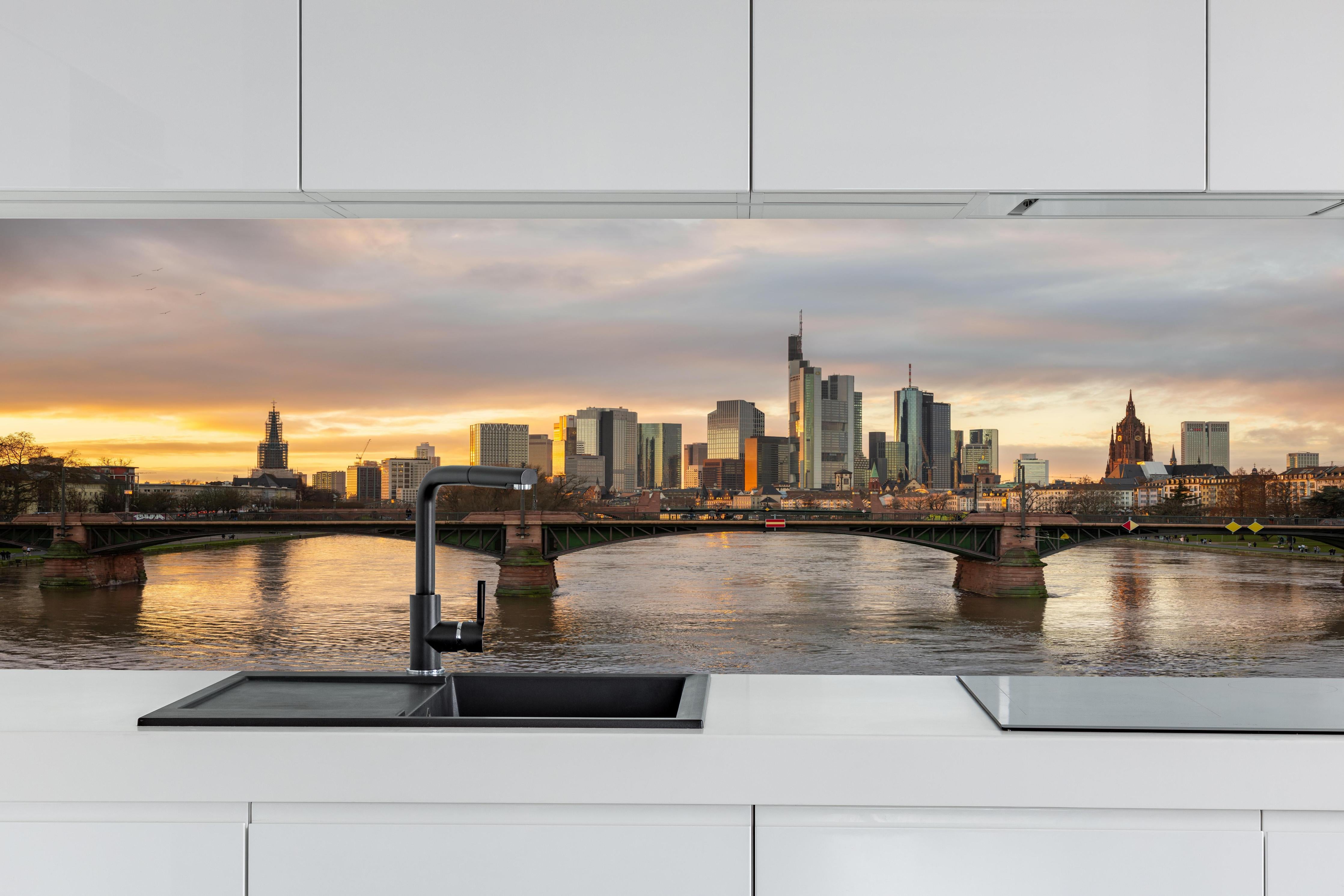 Küche - Stadt-Skyline im Abendlicht hinter weißen Hochglanz-Küchenregalen und schwarzem Wasserhahn