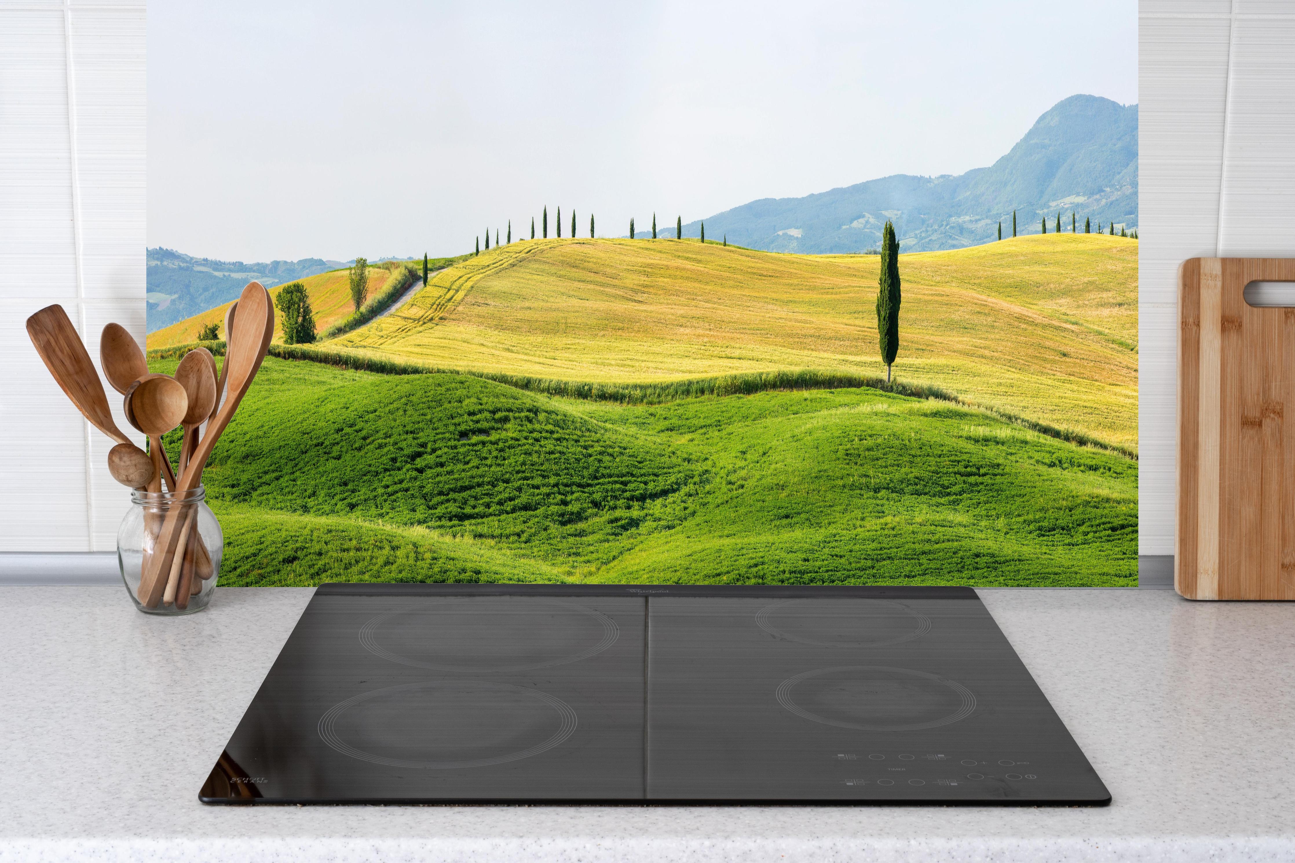 Küche - Toskana Hügel Panorama Grün-Gelb hinter Cerankochfeld und Holz-Kochutensilien