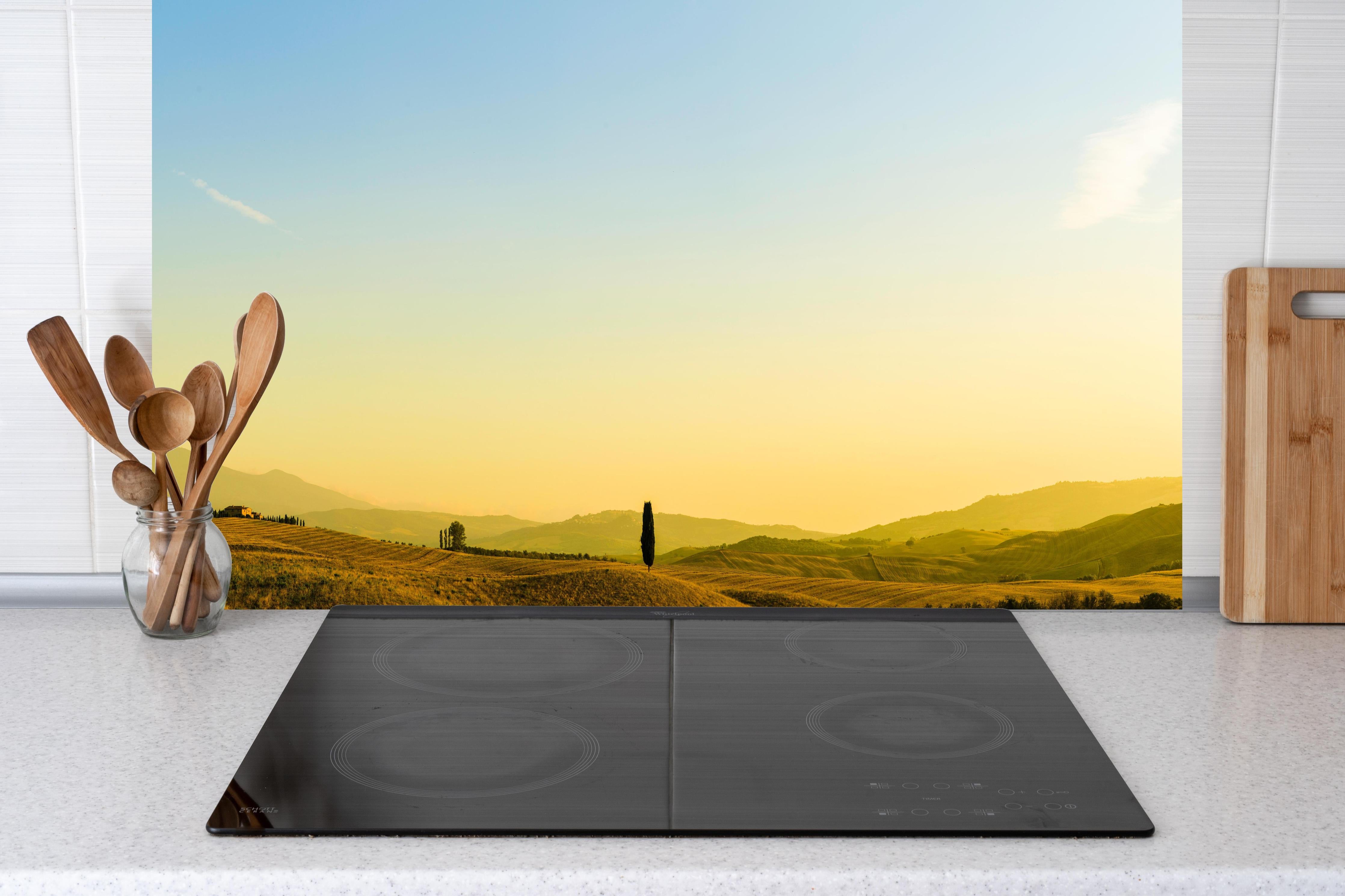 Küche - Toskanische Hügel im Abendlicht hinter Cerankochfeld und Holz-Kochutensilien