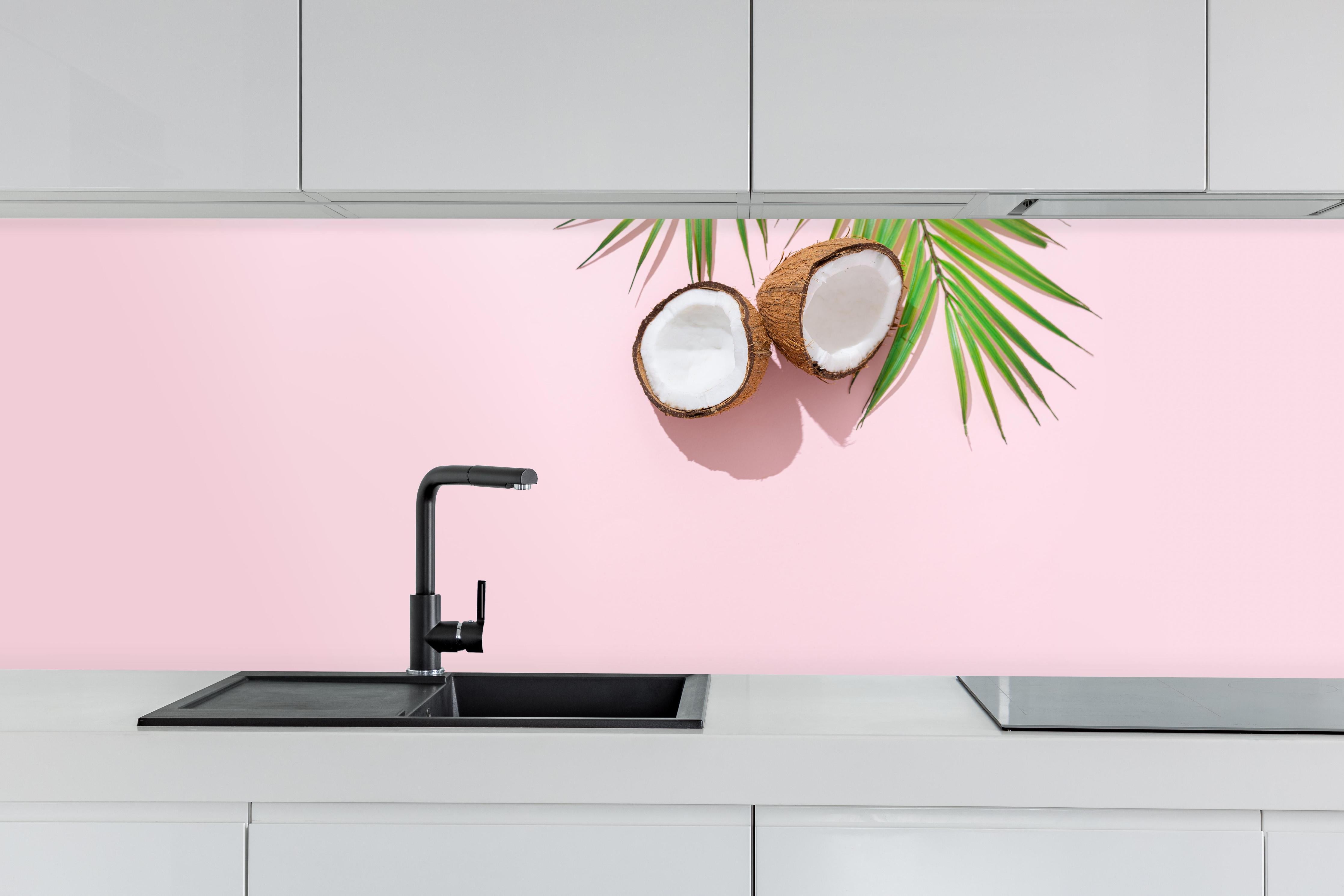 Küche - Tropische Kokosnuss auf Rosa hinter weißen Hochglanz-Küchenregalen und schwarzem Wasserhahn