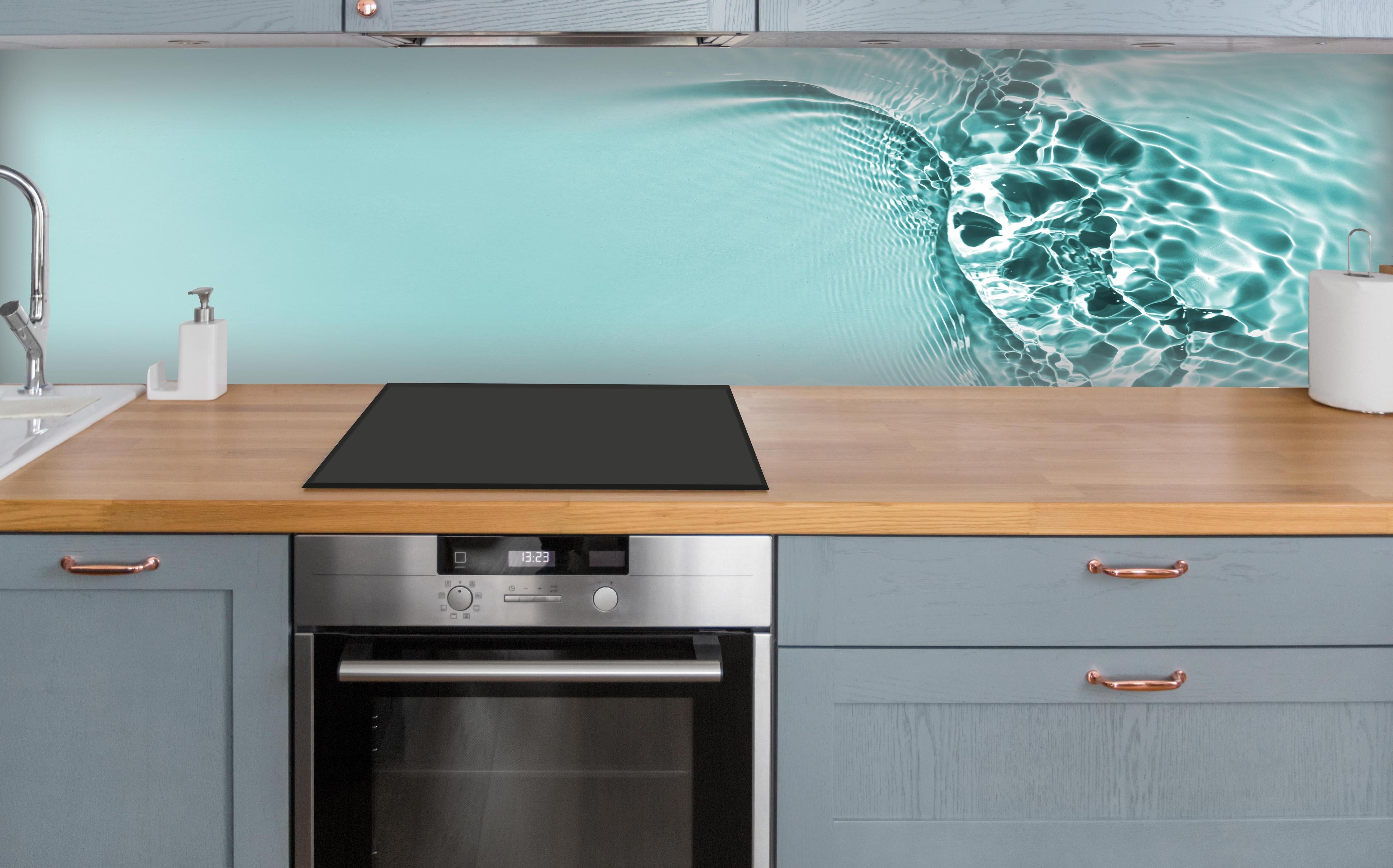 Küche - Türkisblaues Wasser mit Lichtreflexen über polierter Holzarbeitsplatte mit Cerankochfeld