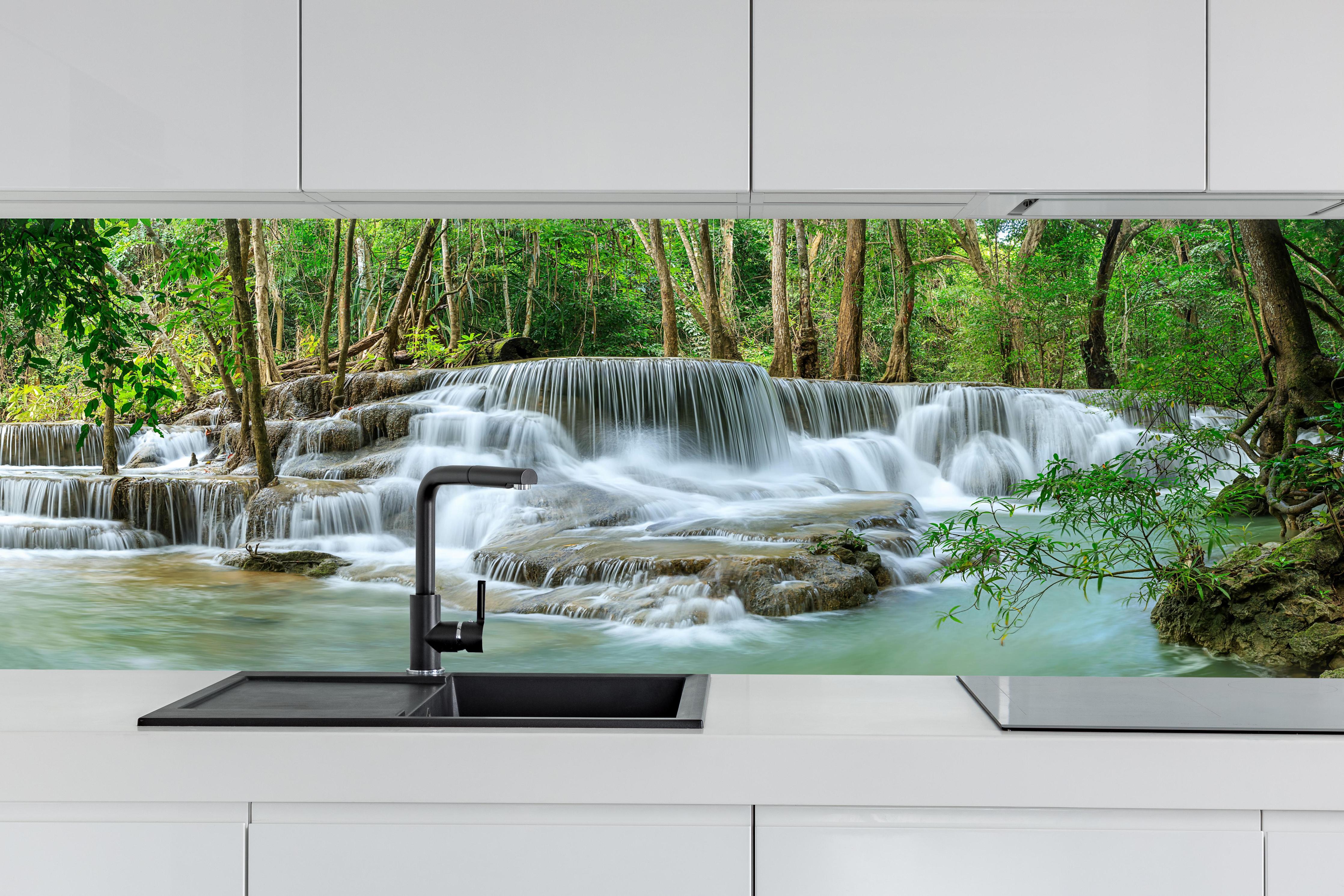 Küche - Türkisgrüner Wasserfall im Wald hinter weißen Hochglanz-Küchenregalen und schwarzem Wasserhahn