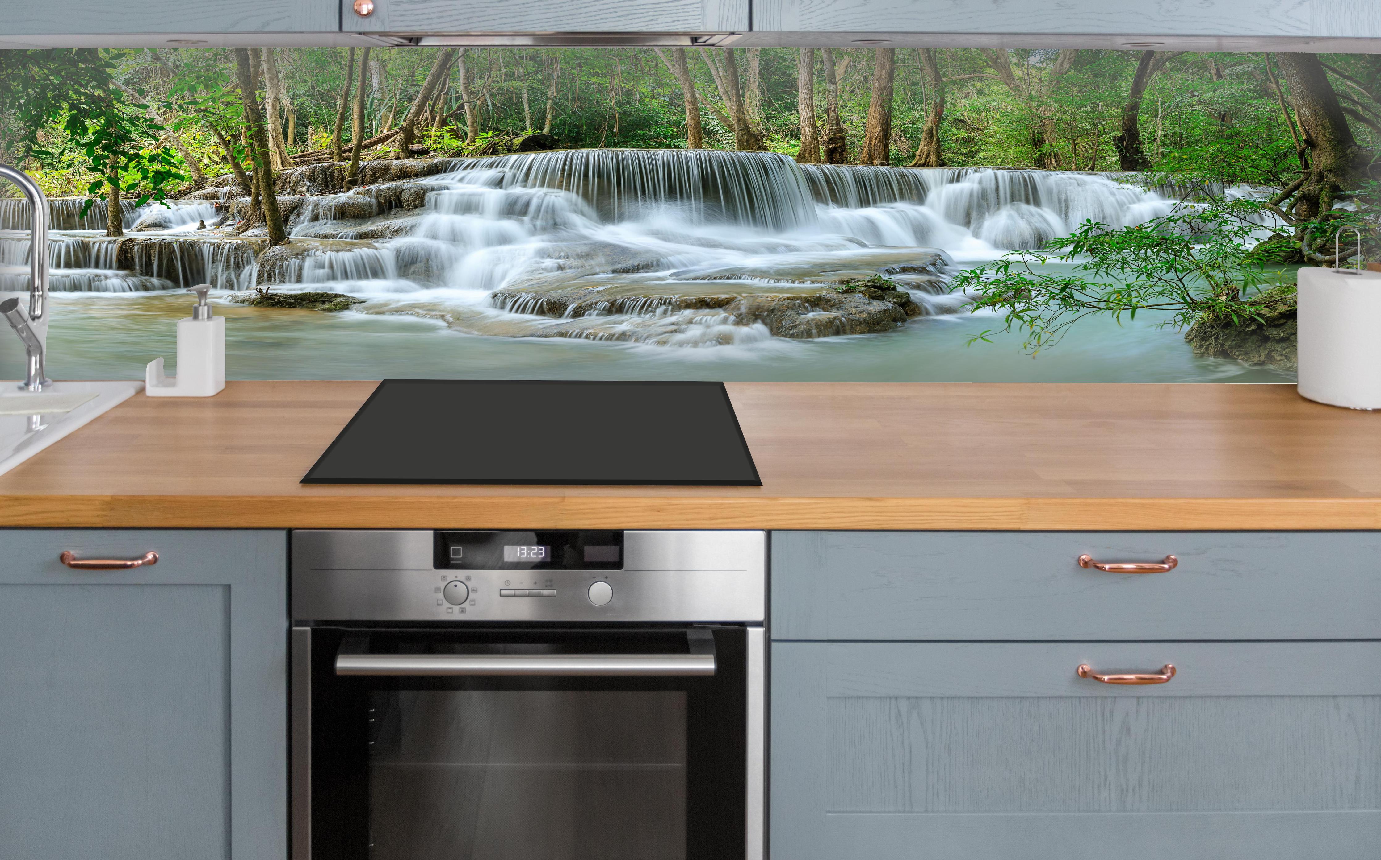 Küche - Türkisgrüner Wasserfall im Wald über polierter Holzarbeitsplatte mit Cerankochfeld