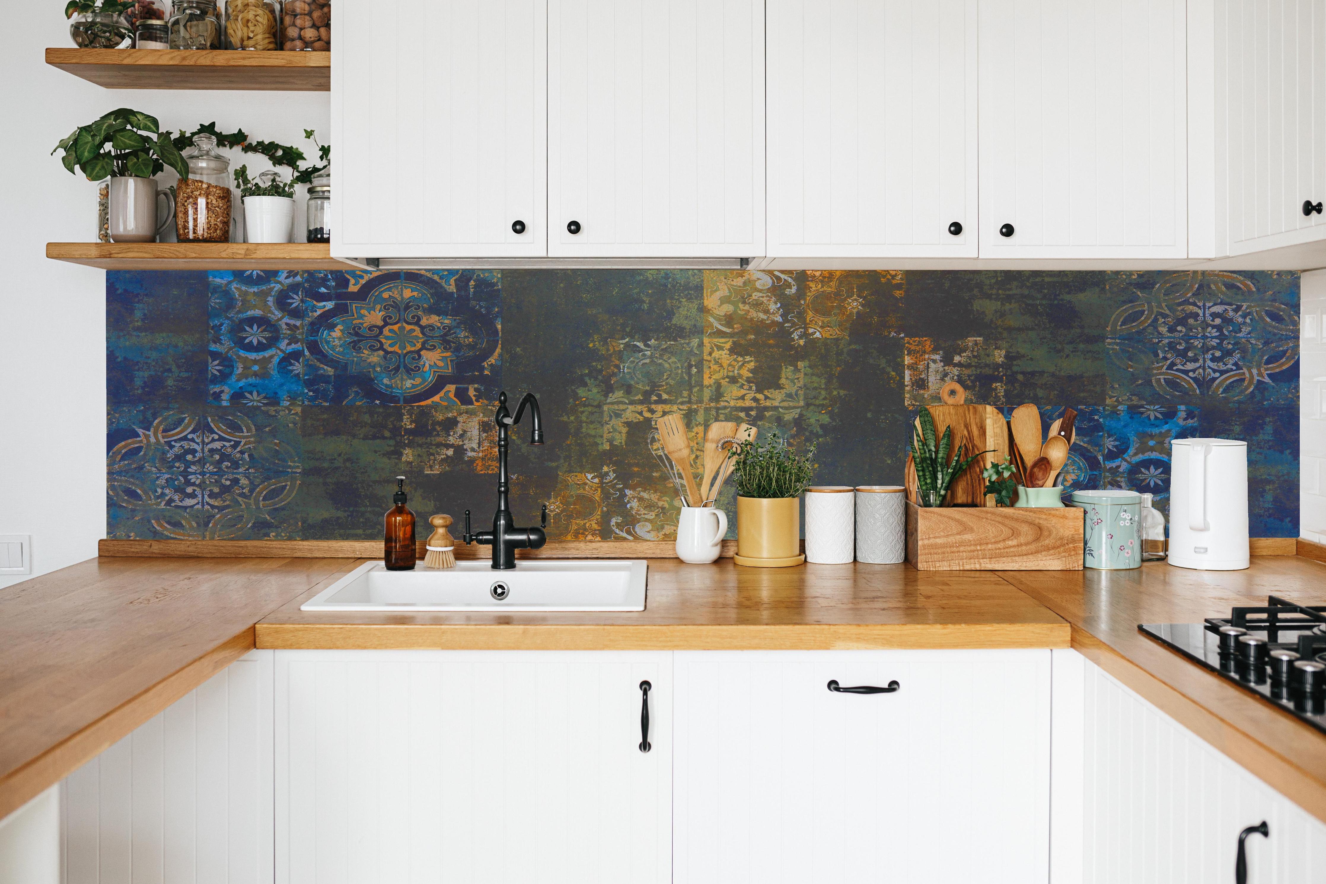 Küche - Vintage Steinfliesen in Blau-Gold in weißer Küche hinter Gewürzen und Kochlöffeln aus Holz