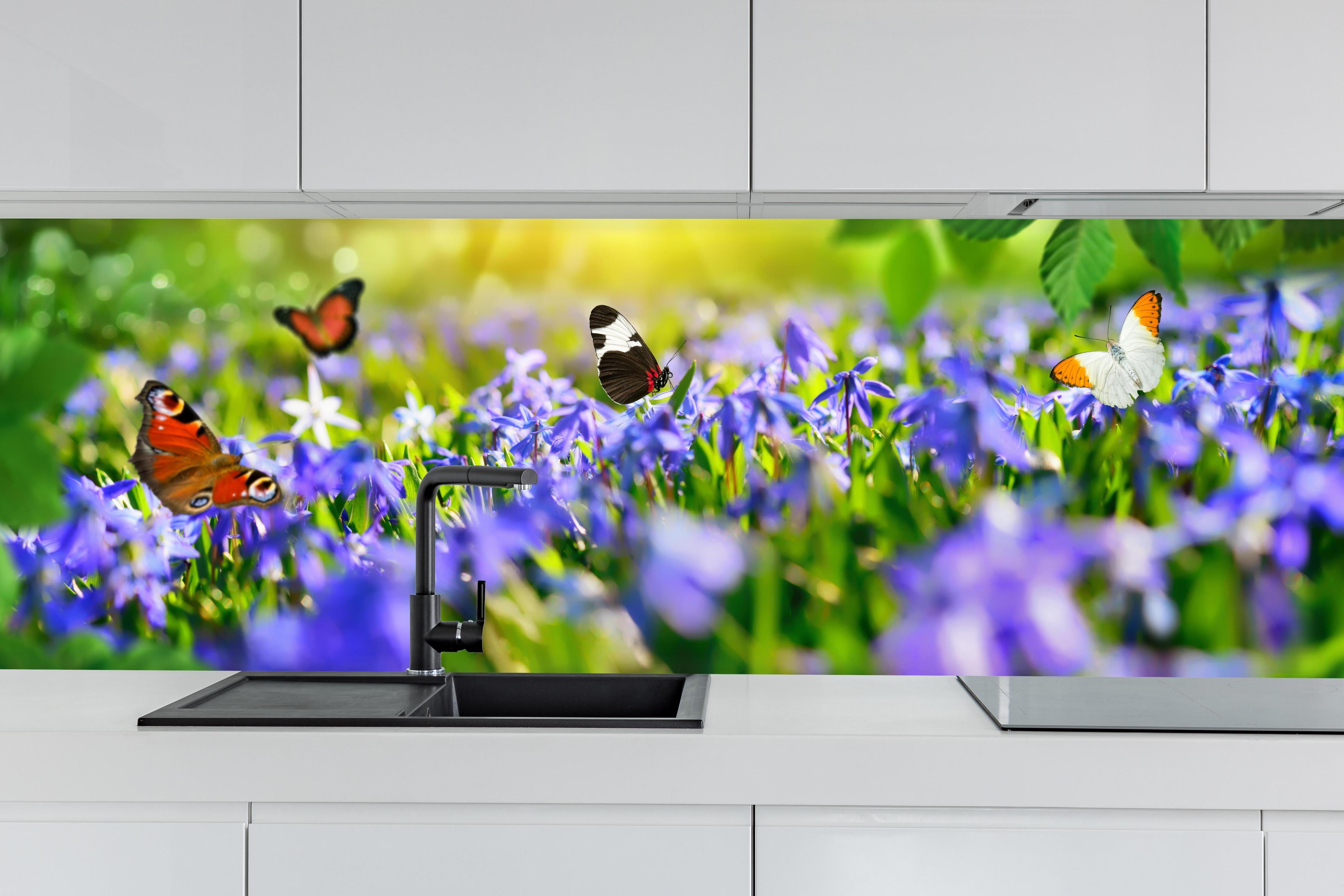 Küche - Violette Blumenwiese mit Schmetterlingen hinter weißen Hochglanz-Küchenregalen und schwarzem Wasserhahn