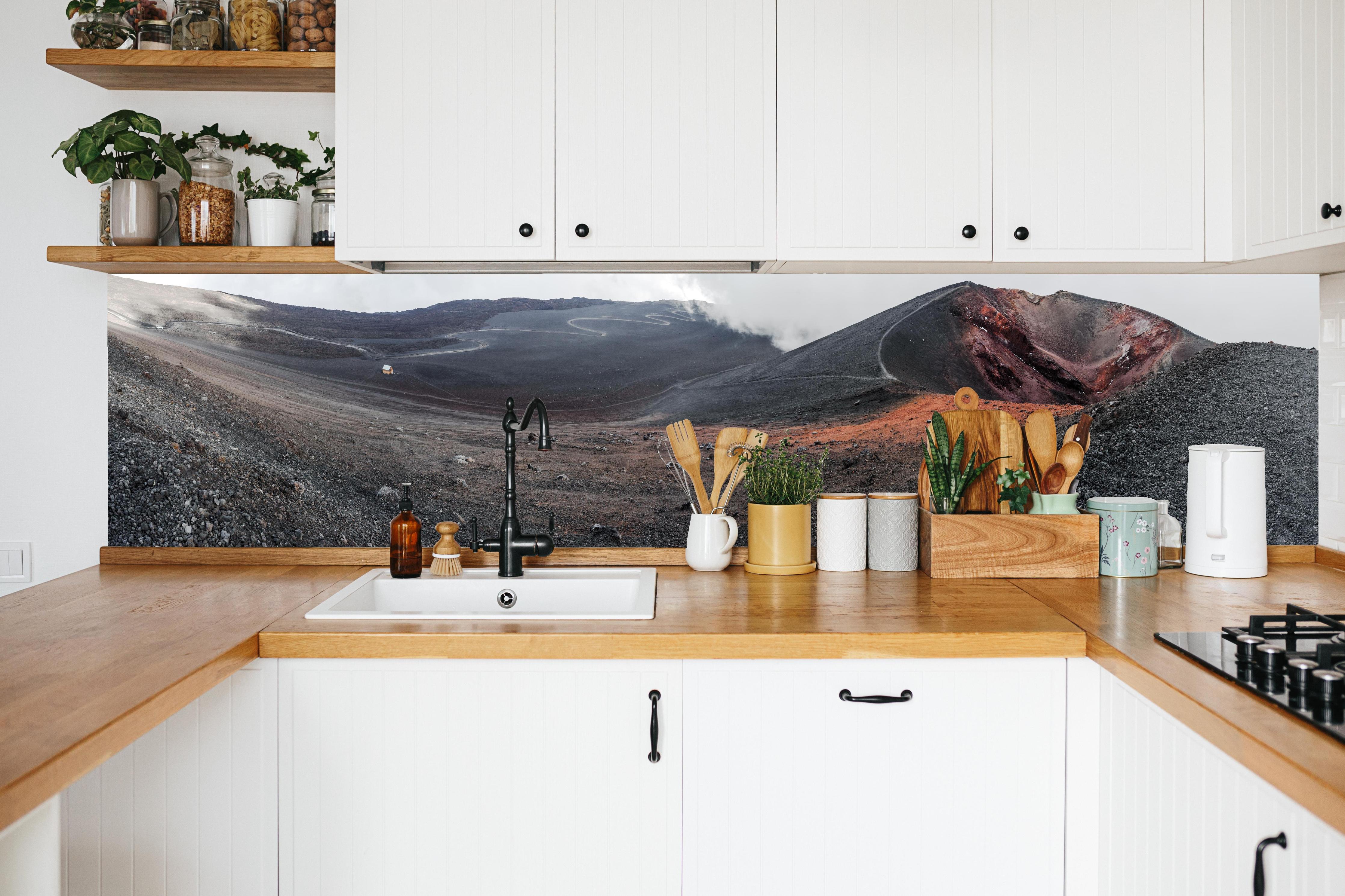 Küche - Vulkankrater Schwarz-Grau-Orange Panorama in weißer Küche hinter Gewürzen und Kochlöffeln aus Holz