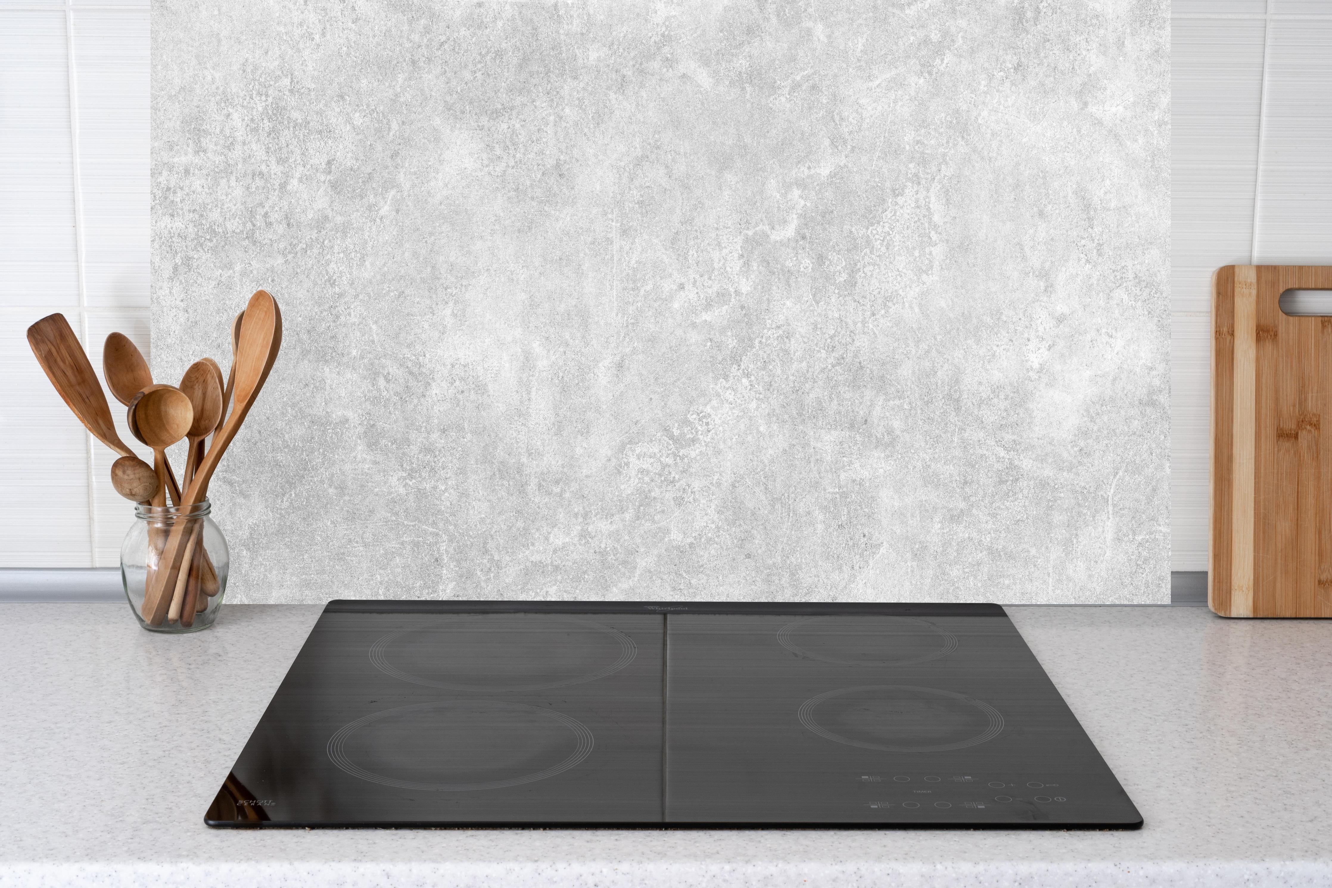 Küche - Weiß-Grau Betonstruktur hinter Cerankochfeld und Holz-Kochutensilien