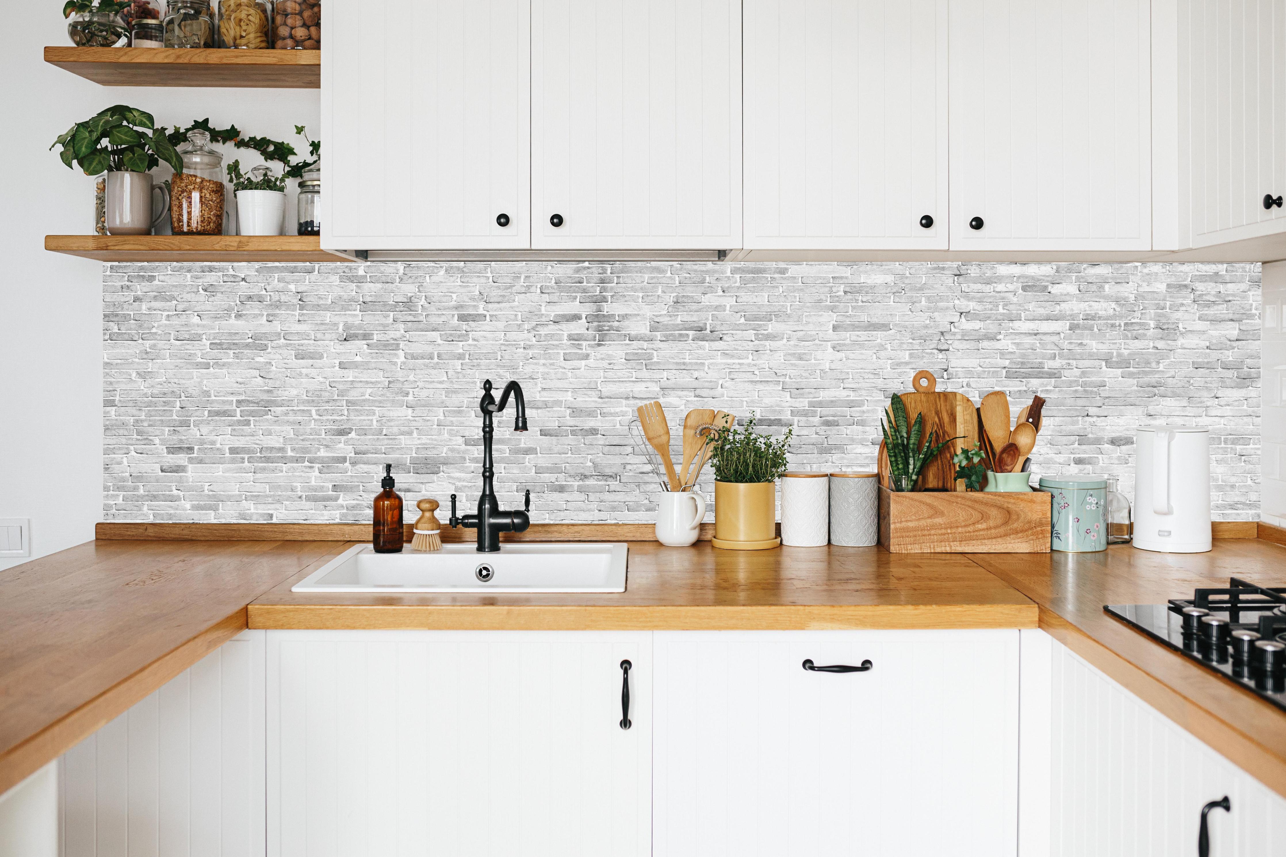Küche - Weiß-Grau-Ziegeltextur in weißer Küche hinter Gewürzen und Kochlöffeln aus Holz