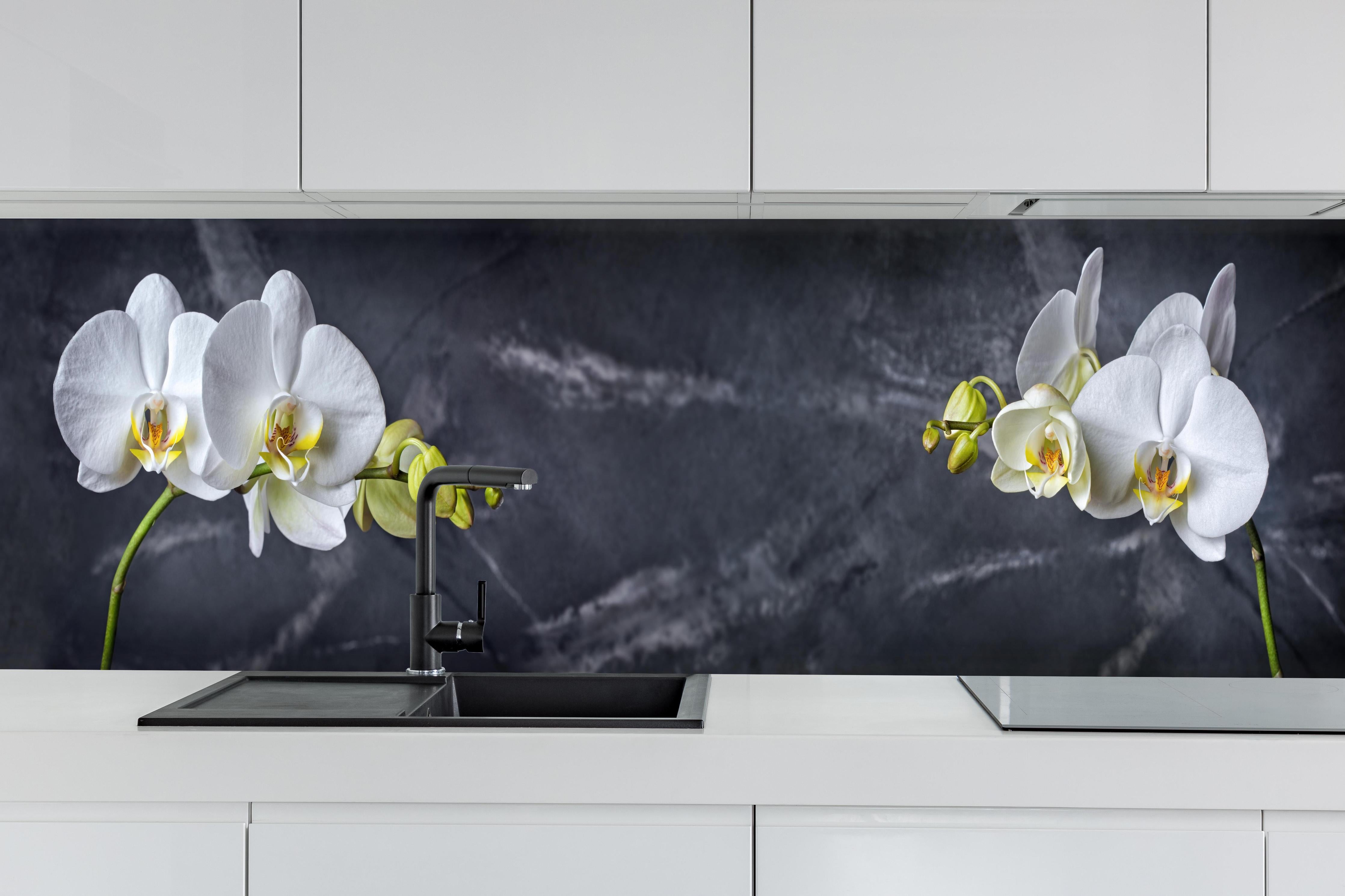 Küche - Weiße Orchideen auf Marmor hinter weißen Hochglanz-Küchenregalen und schwarzem Wasserhahn
