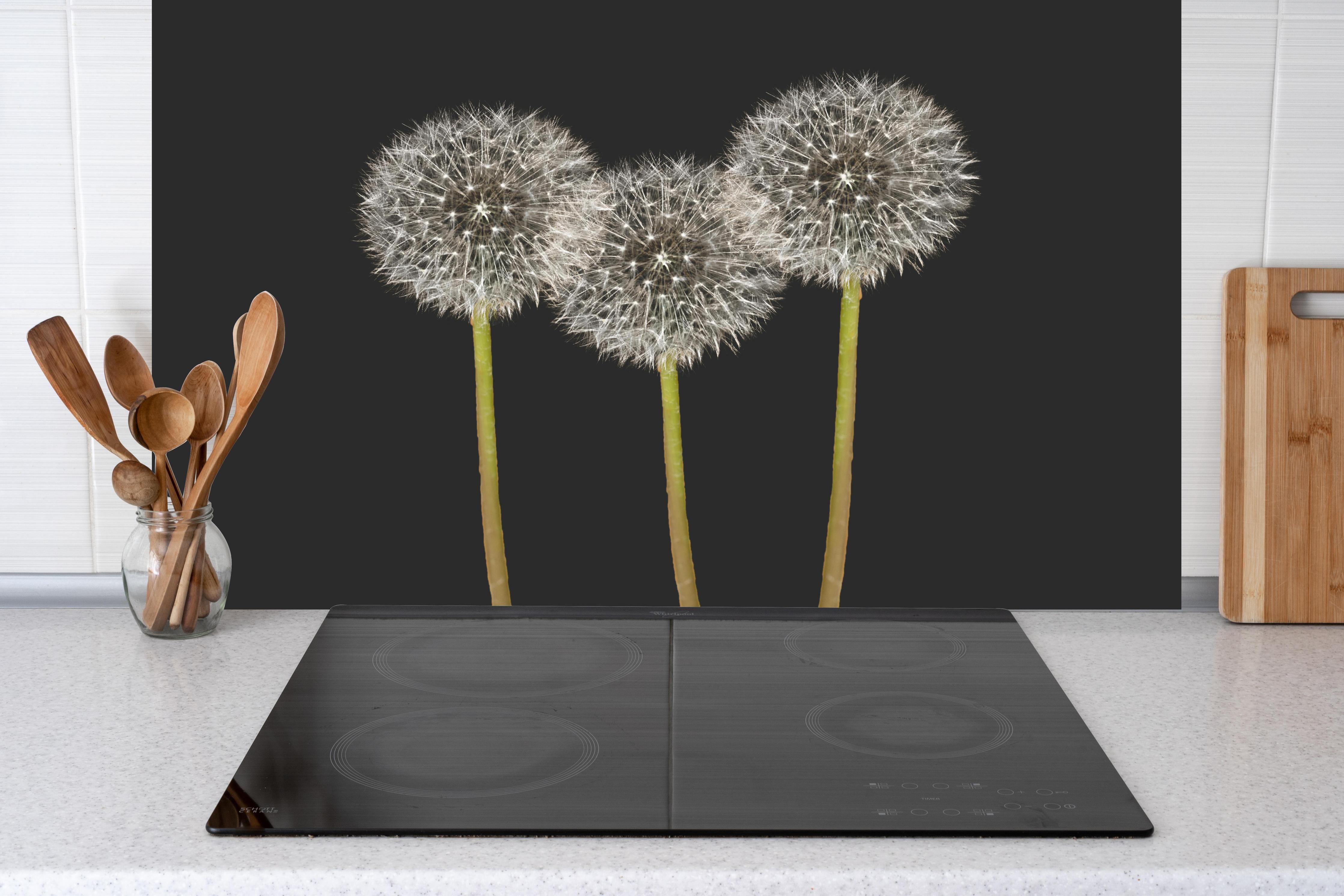 Küche - Weiße Pusteblumen auf Schwarz hinter Cerankochfeld und Holz-Kochutensilien
