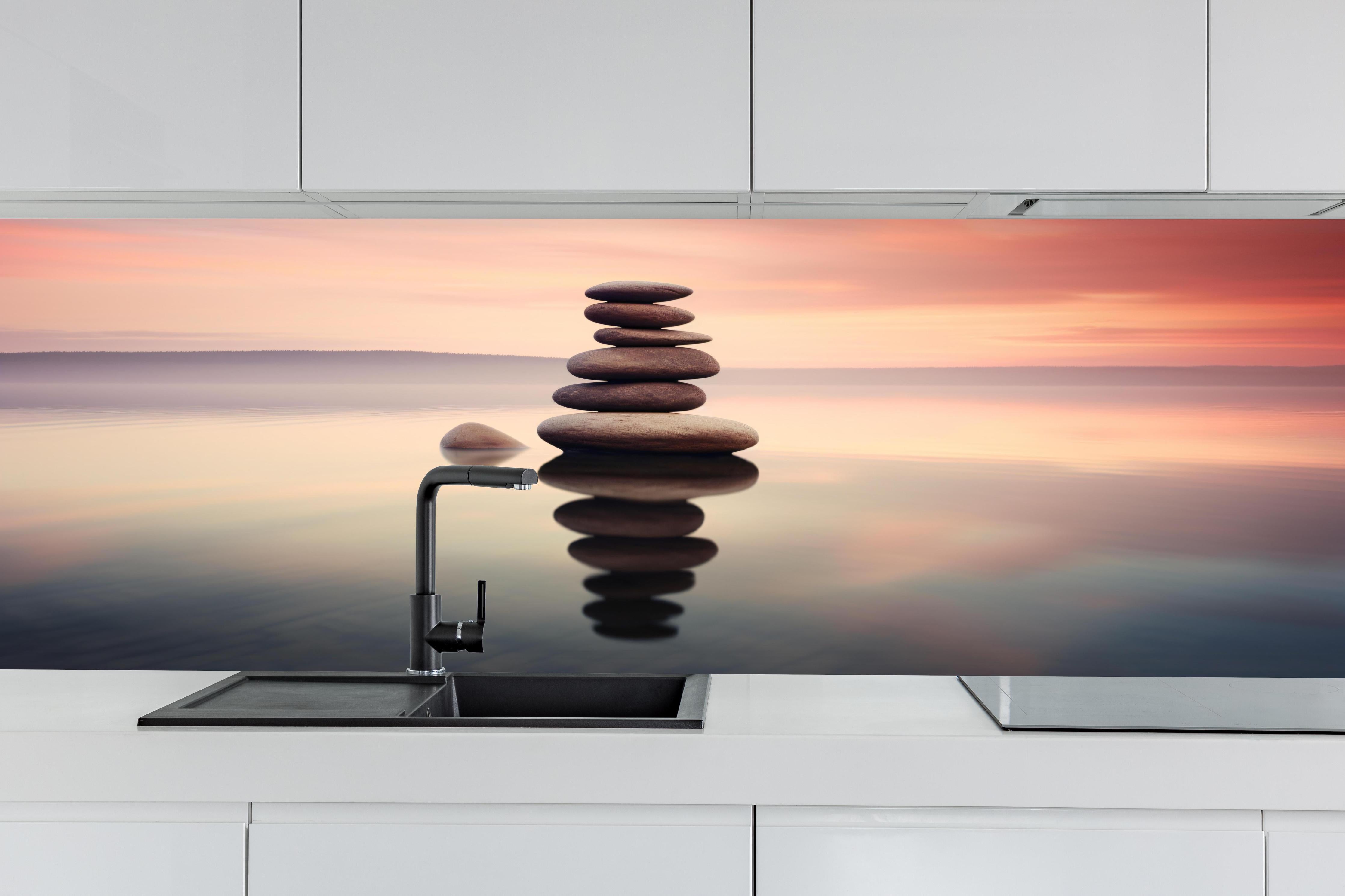Küche - Zen-Steine am rosa Sonnenuntergang hinter weißen Hochglanz-Küchenregalen und schwarzem Wasserhahn