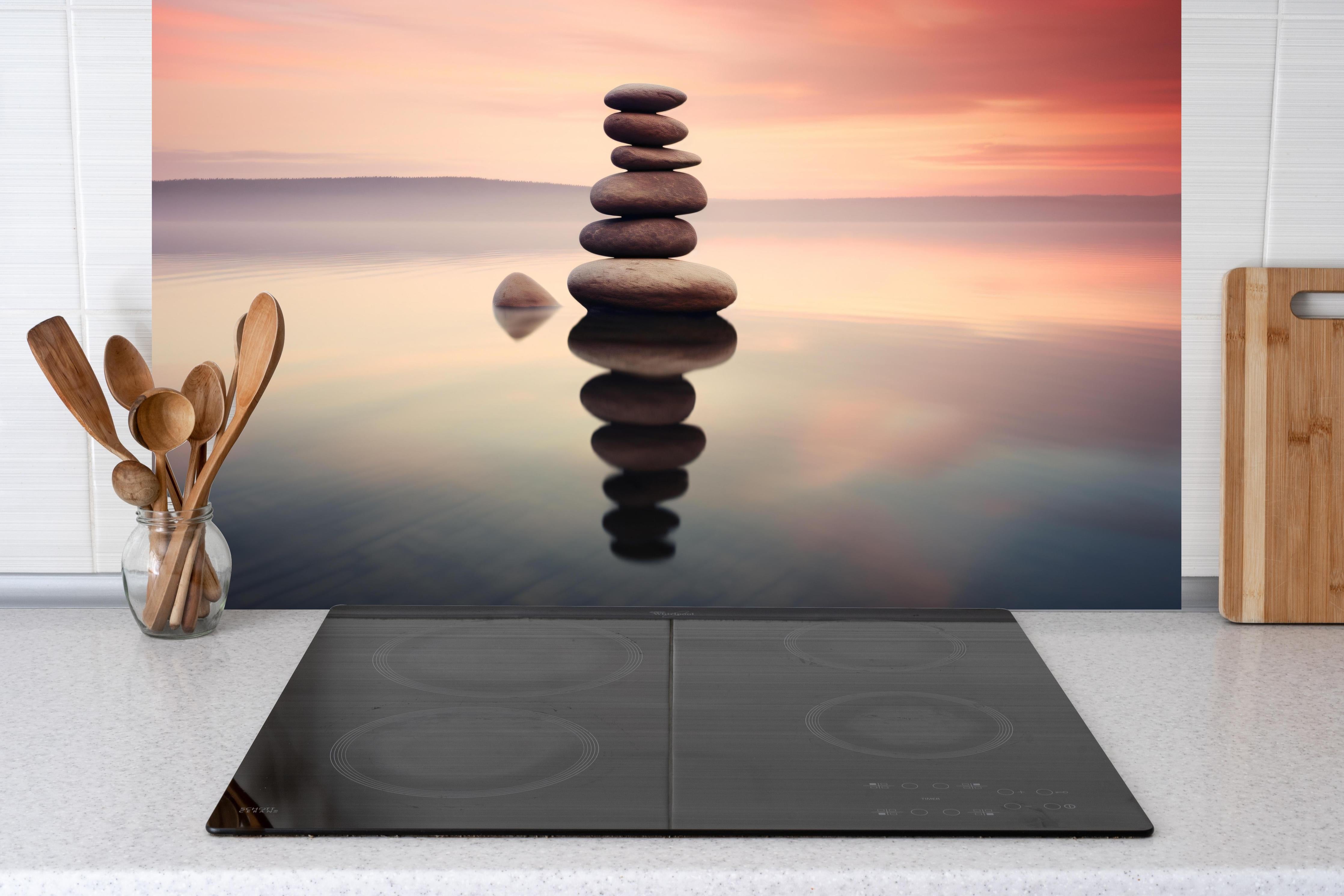 Küche - Zen-Steine am rosa Sonnenuntergang hinter Cerankochfeld und Holz-Kochutensilien