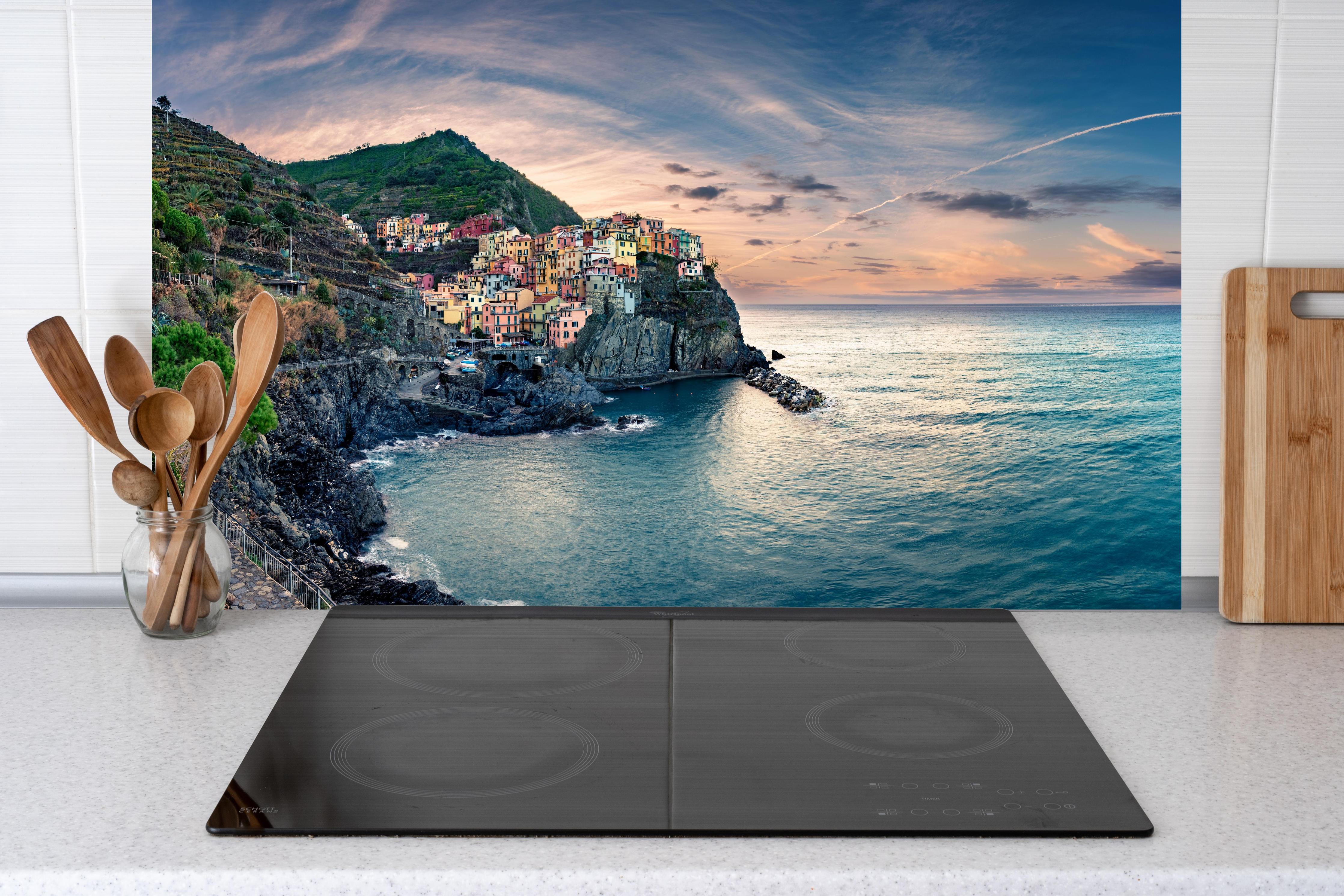 Küche - talienische Küste im Abendrot hinter Cerankochfeld und Holz-Kochutensilien