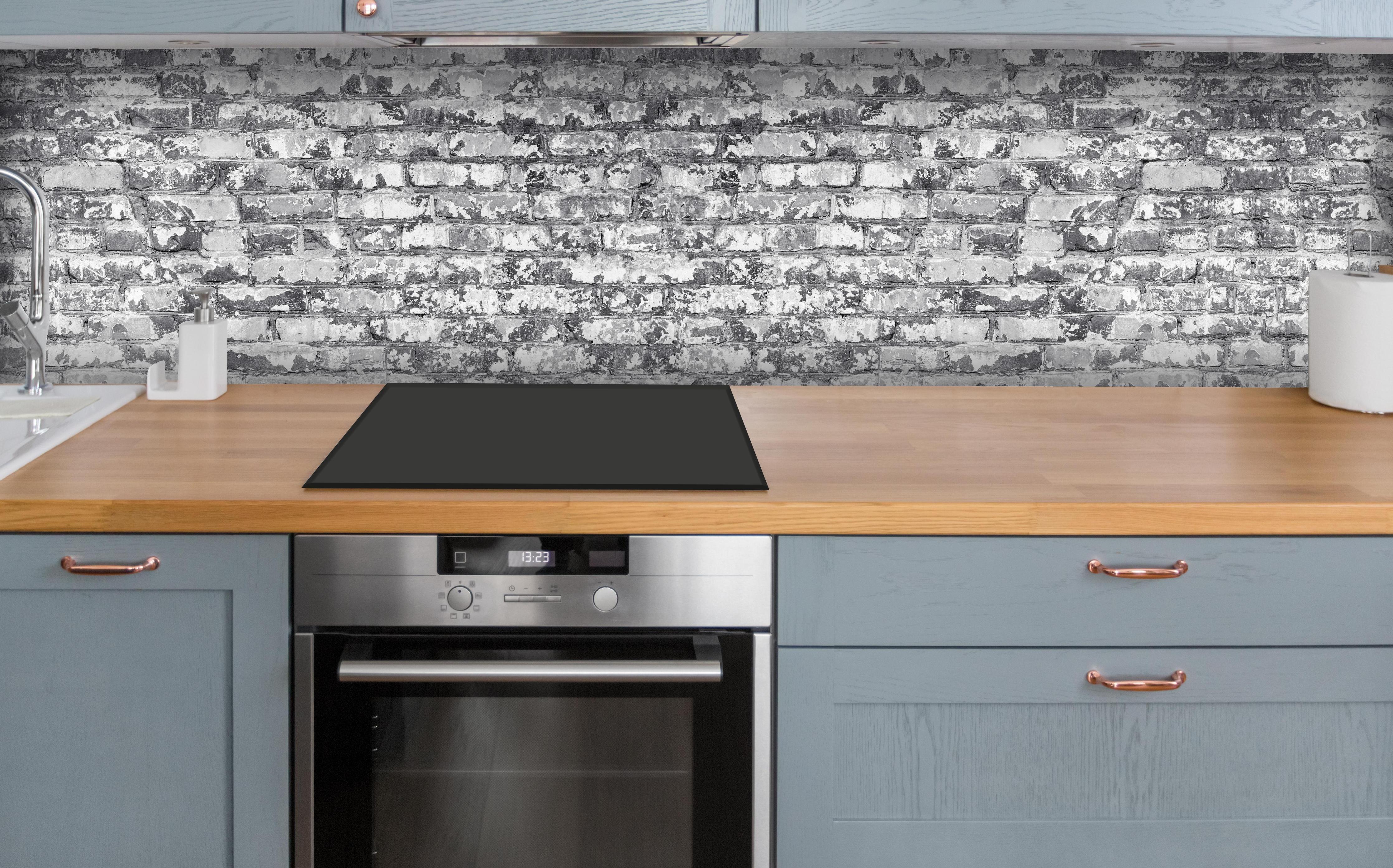 Küche - Hellgraue verwitterte Vintage Ziegelwand über polierter Holzarbeitsplatte mit Cerankochfeld