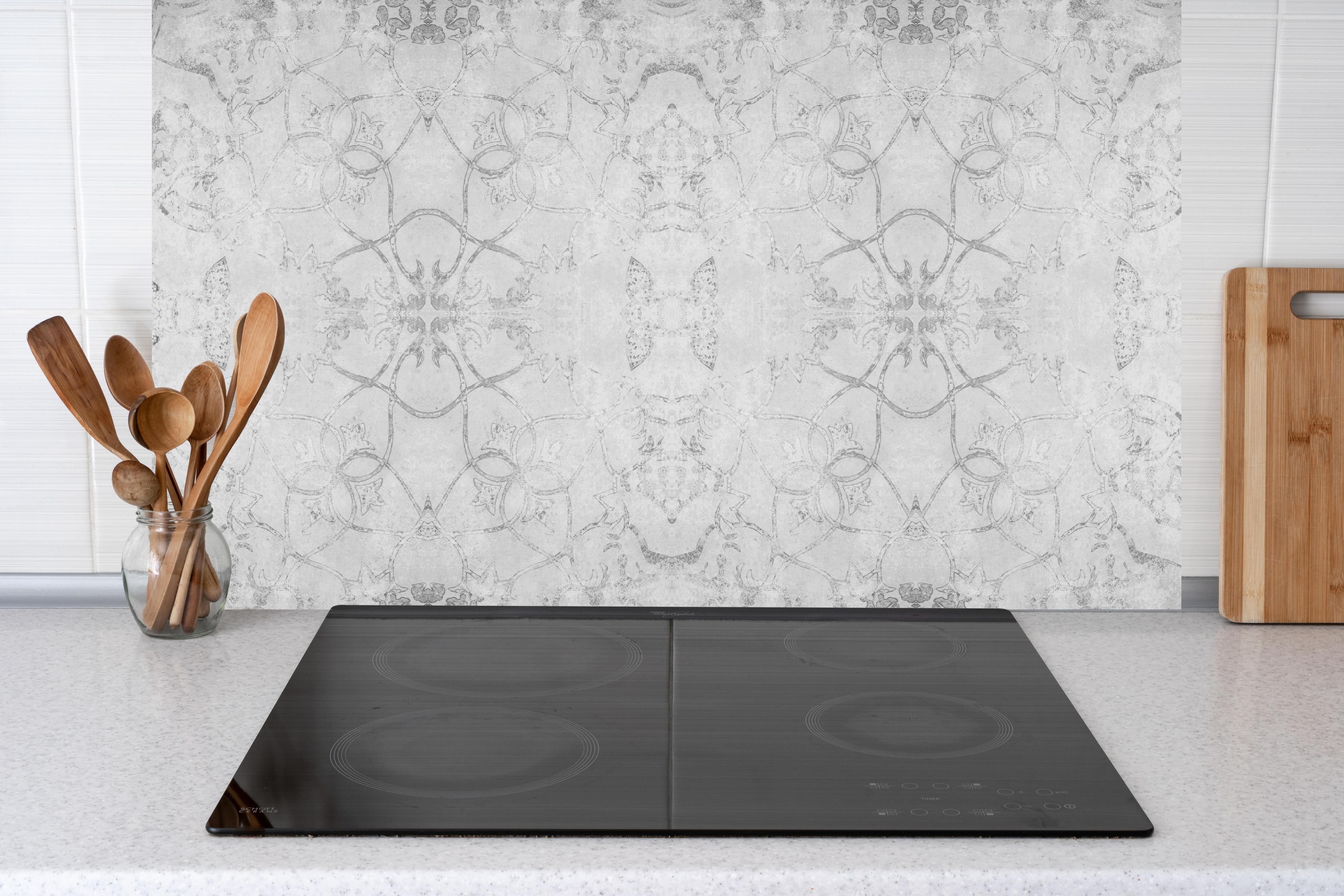 Küche - Abgenutzte weiße Tapetenmuster hinter Cerankochfeld und Holz-Kochutensilien