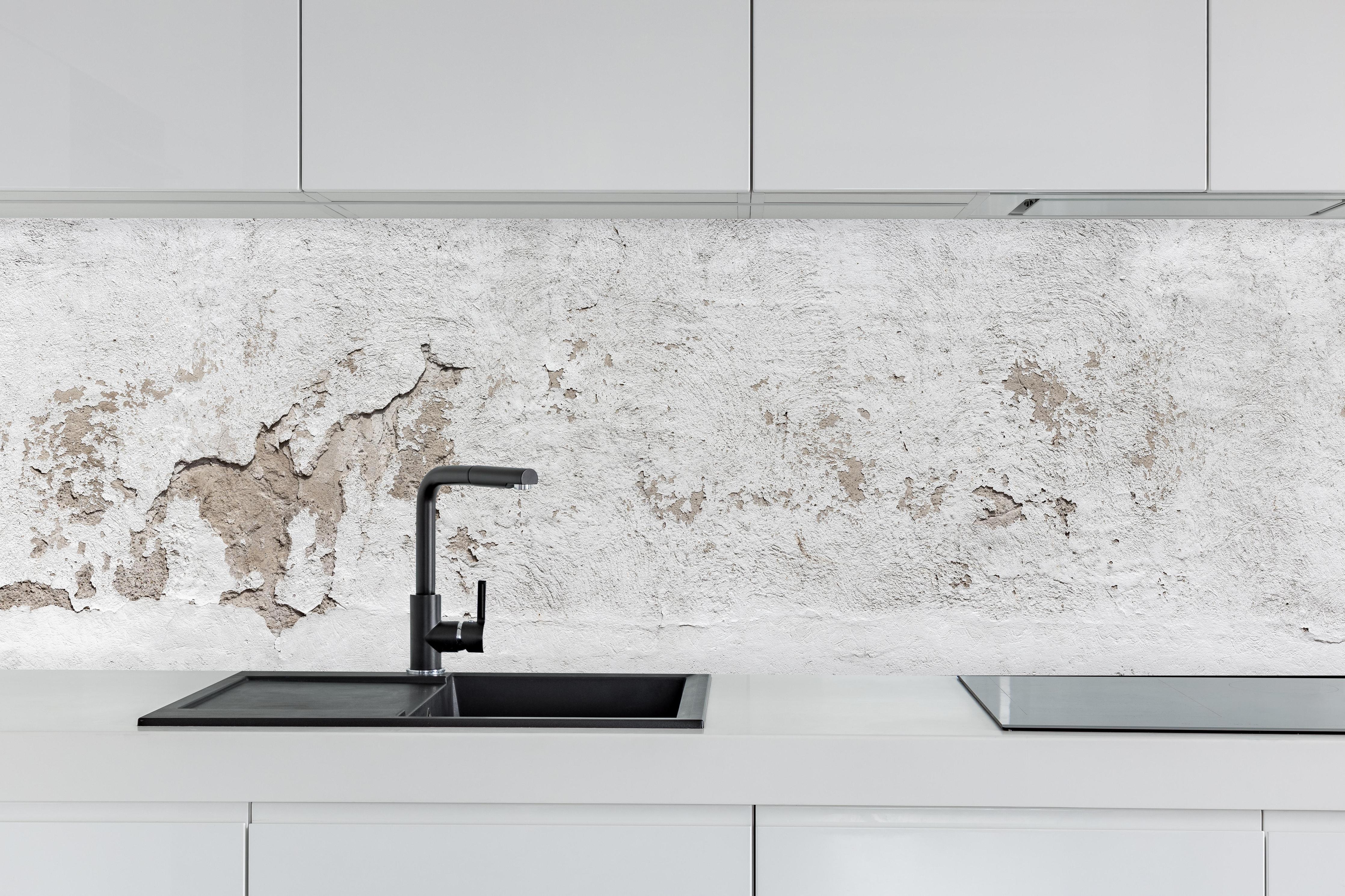 Küche - Alte Mauer mit abblätterndem Putz hinter weißen Hochglanz-Küchenregalen und schwarzem Wasserhahn