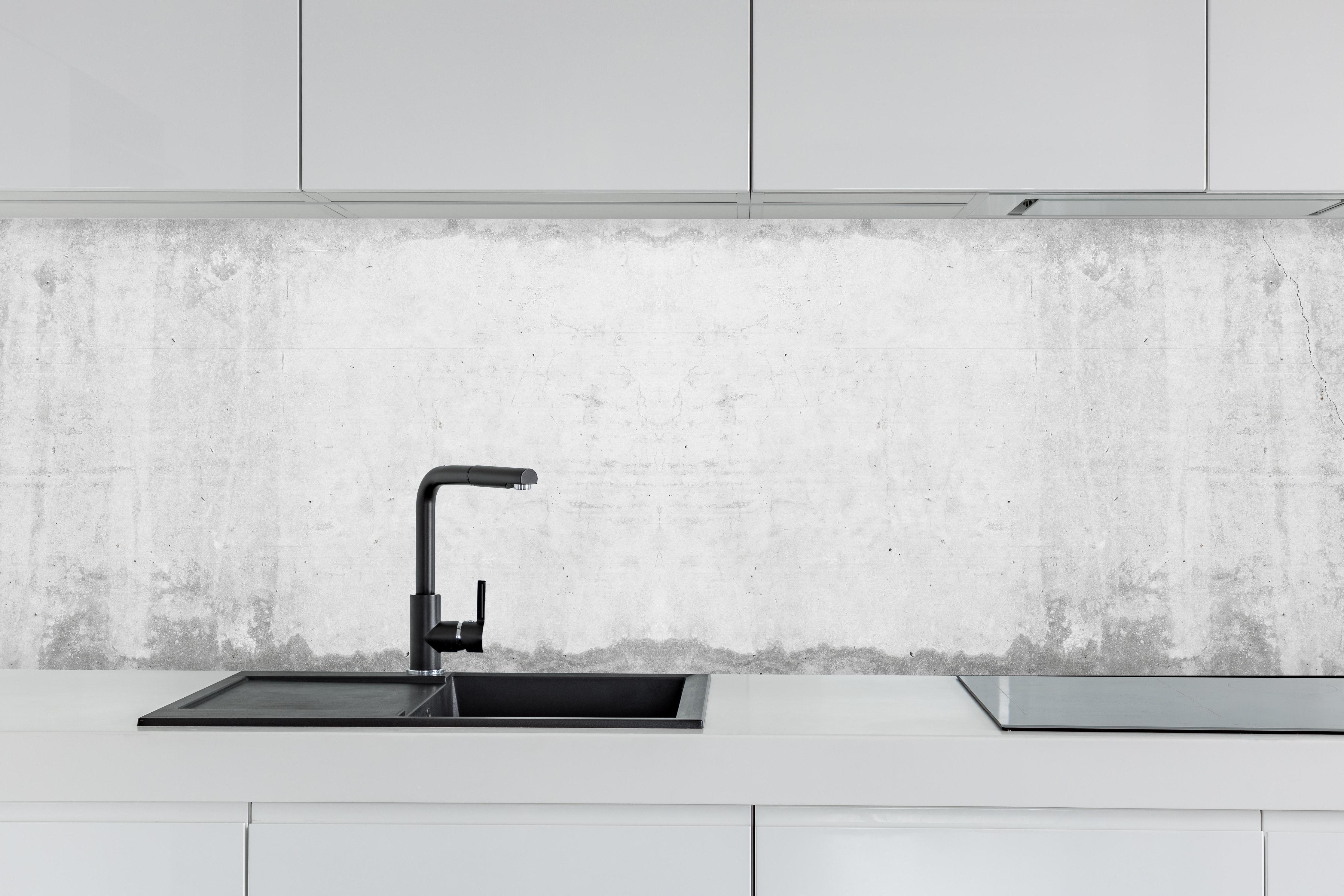 Küche - Alte schmutzige Zementwand hinter weißen Hochglanz-Küchenregalen und schwarzem Wasserhahn