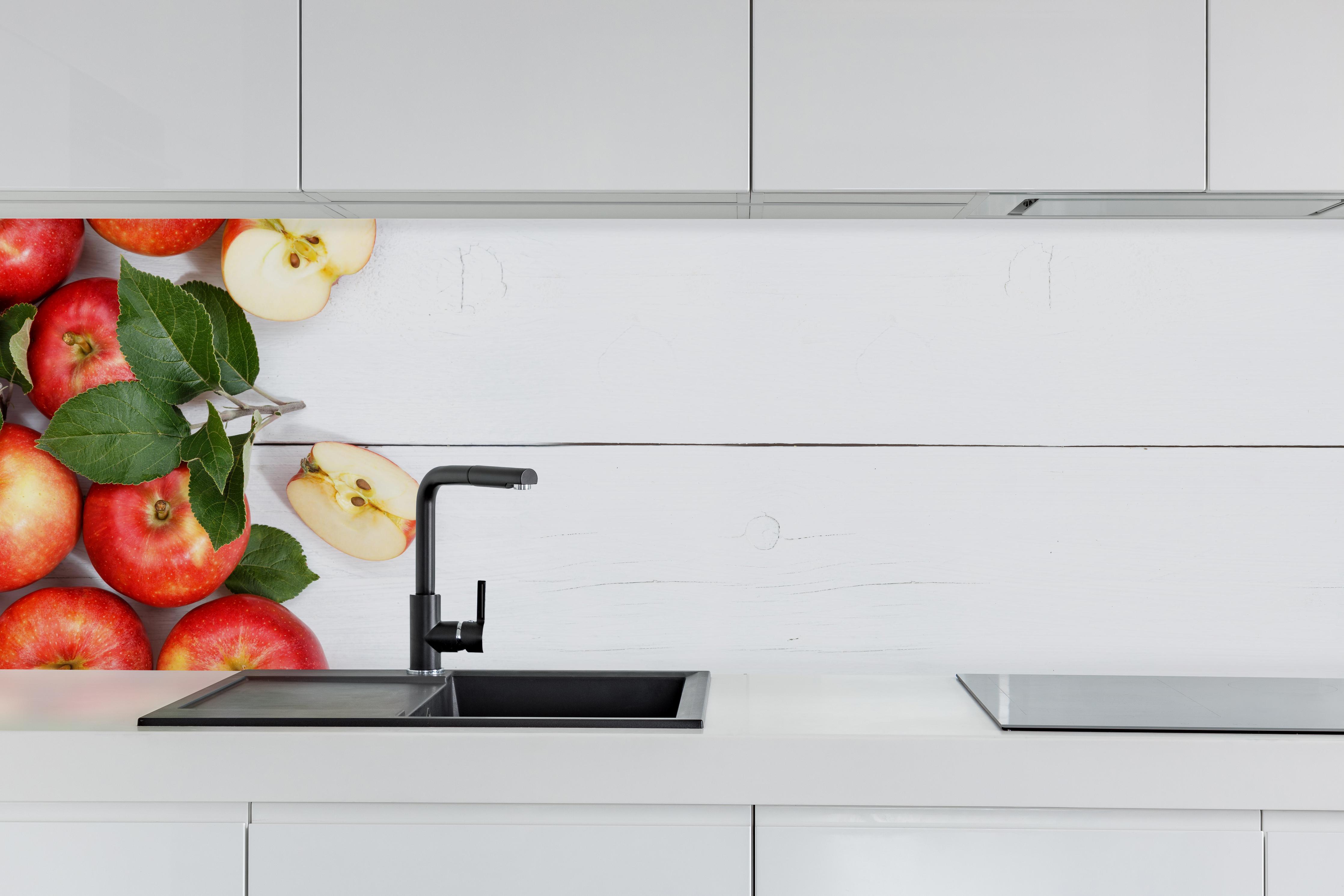 Küche - Äpfel auf weißer Holzplatte hinter weißen Hochglanz-Küchenregalen und schwarzem Wasserhahn