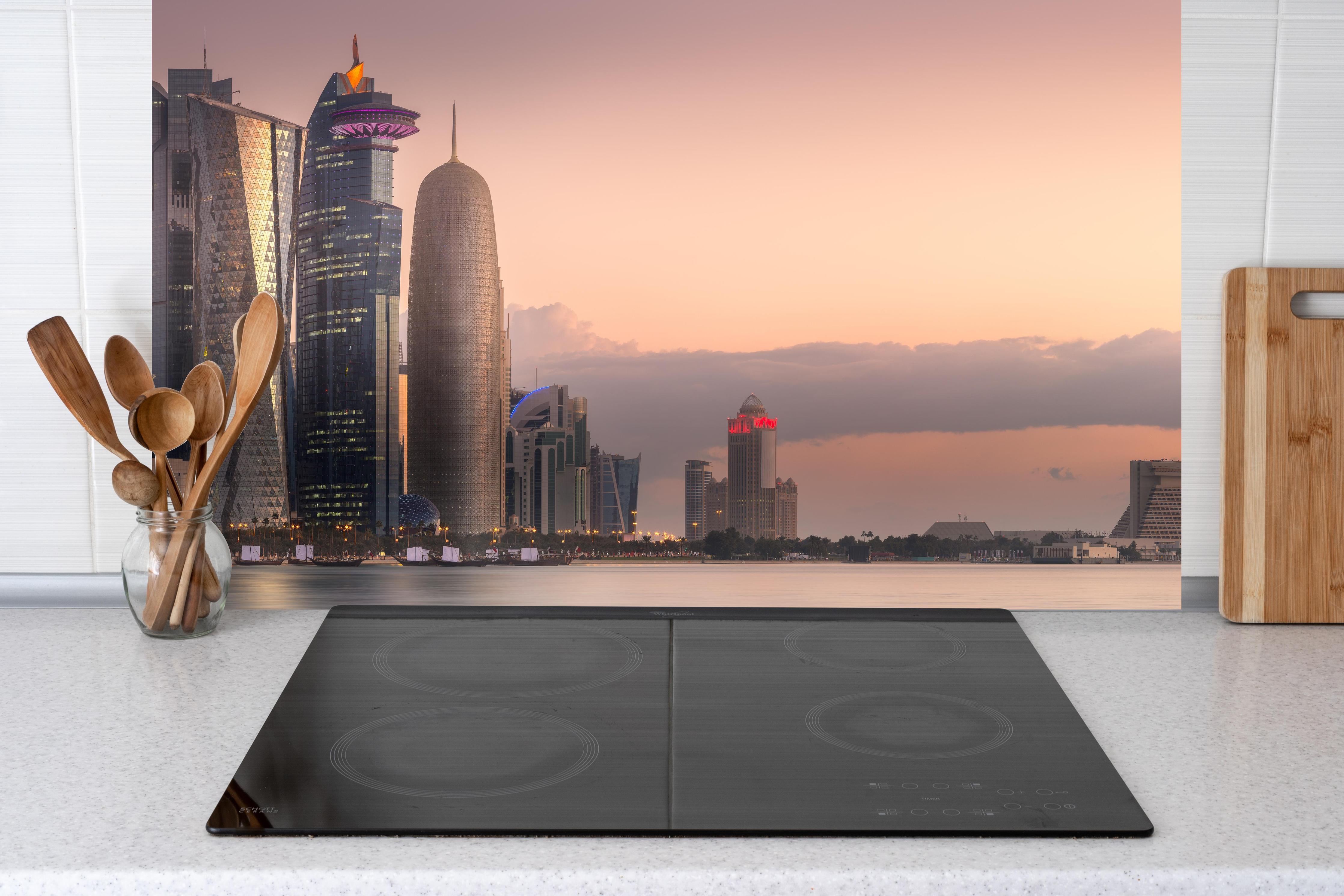 Küche - Die Skyline von West Bay und Doha City hinter Cerankochfeld und Holz-Kochutensilien