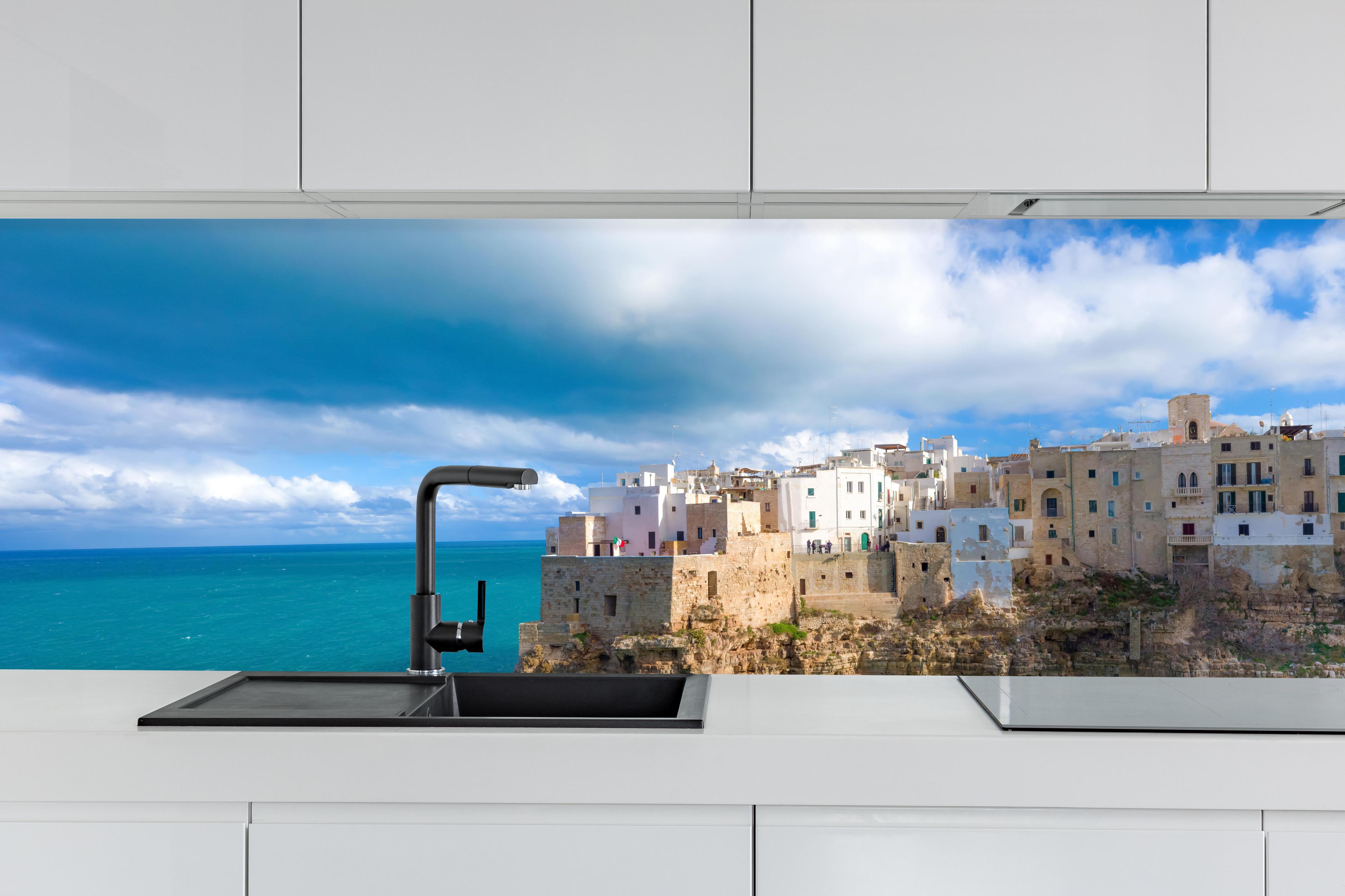 Küche - Drohnensicht - Polignano hinter weißen Hochglanz-Küchenregalen und schwarzem Wasserhahn