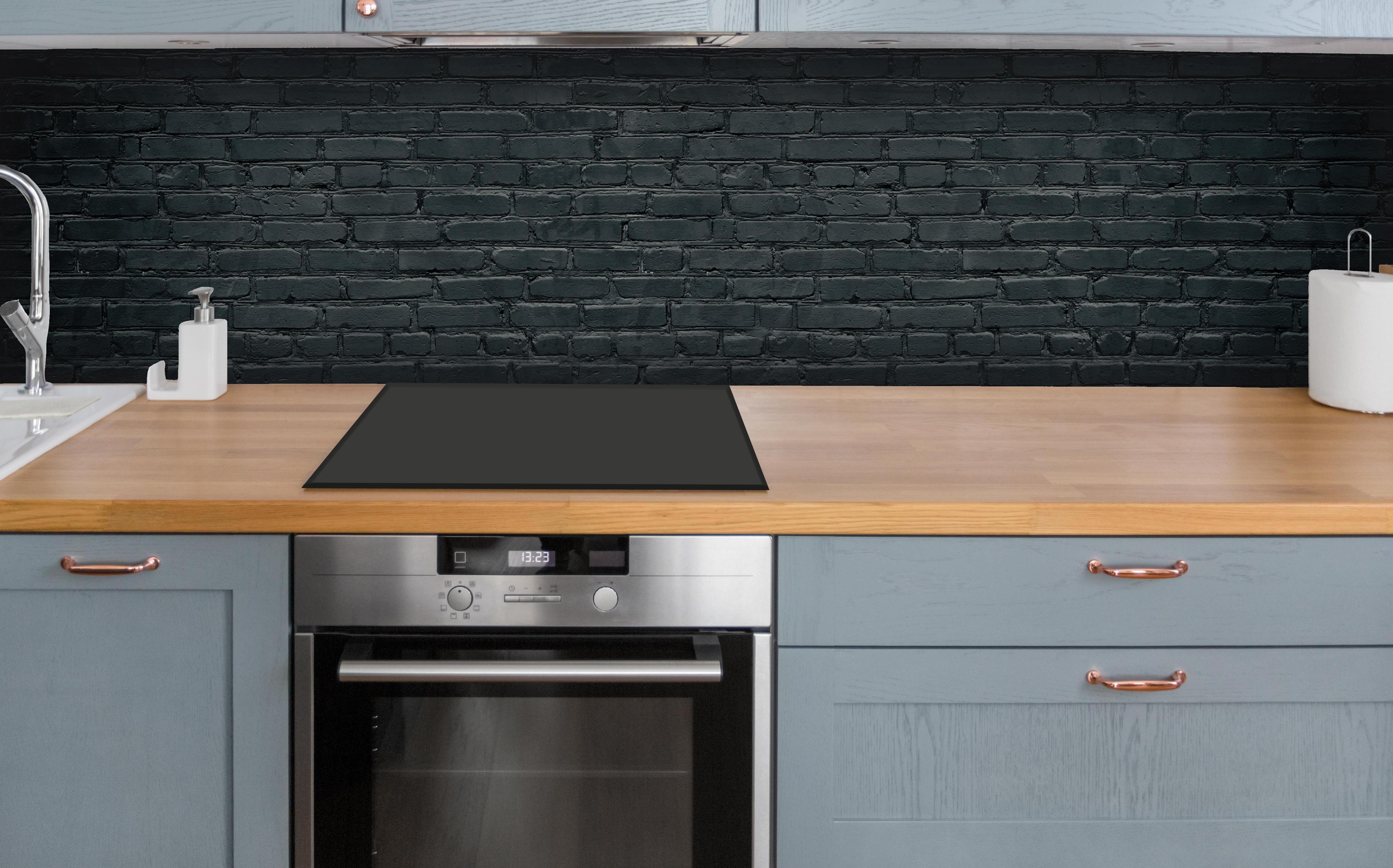 Küche - Gealtertes dunkles Mauerwerk über polierter Holzarbeitsplatte mit Cerankochfeld