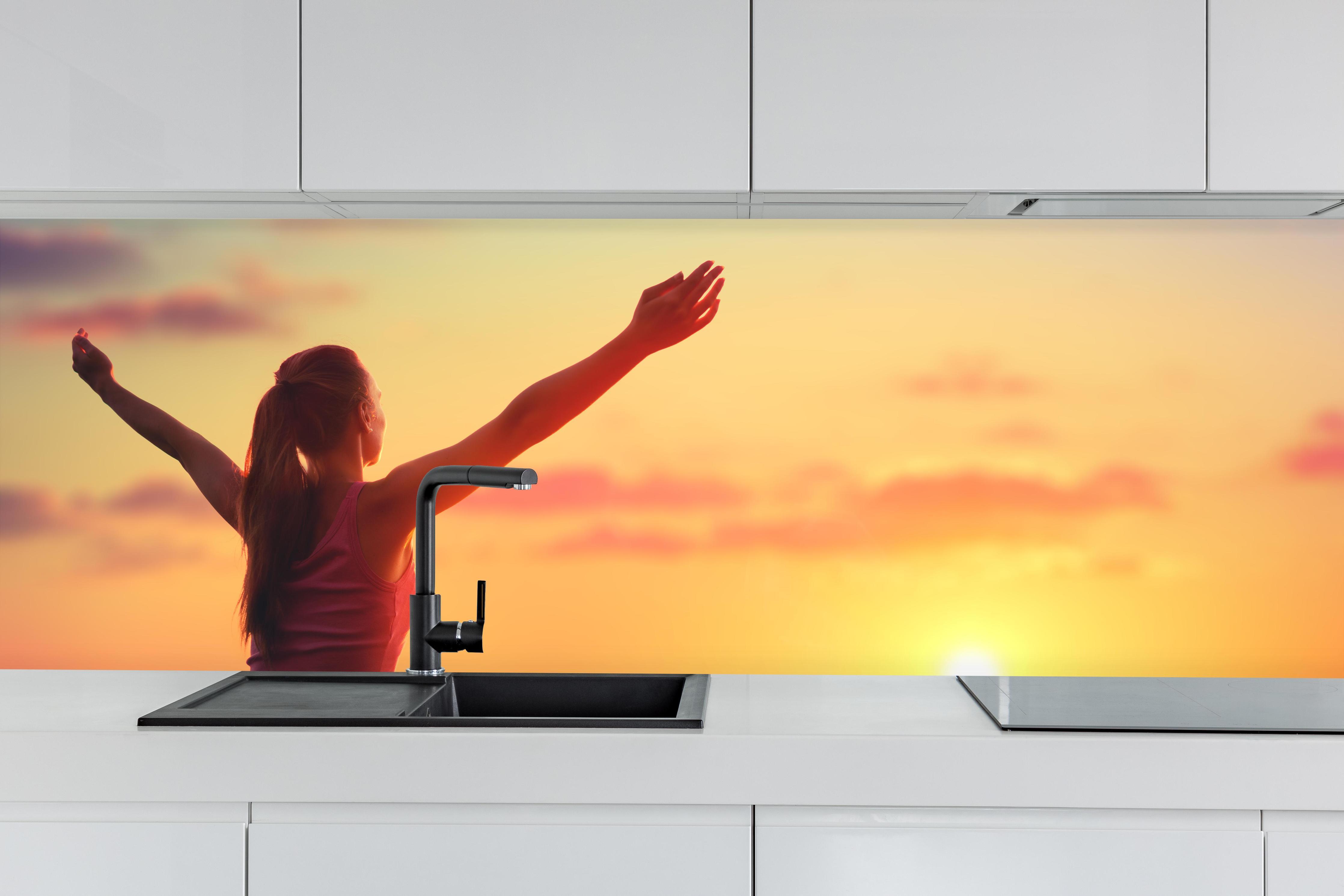 Küche - Glückliche Frau am Strand hinter weißen Hochglanz-Küchenregalen und schwarzem Wasserhahn