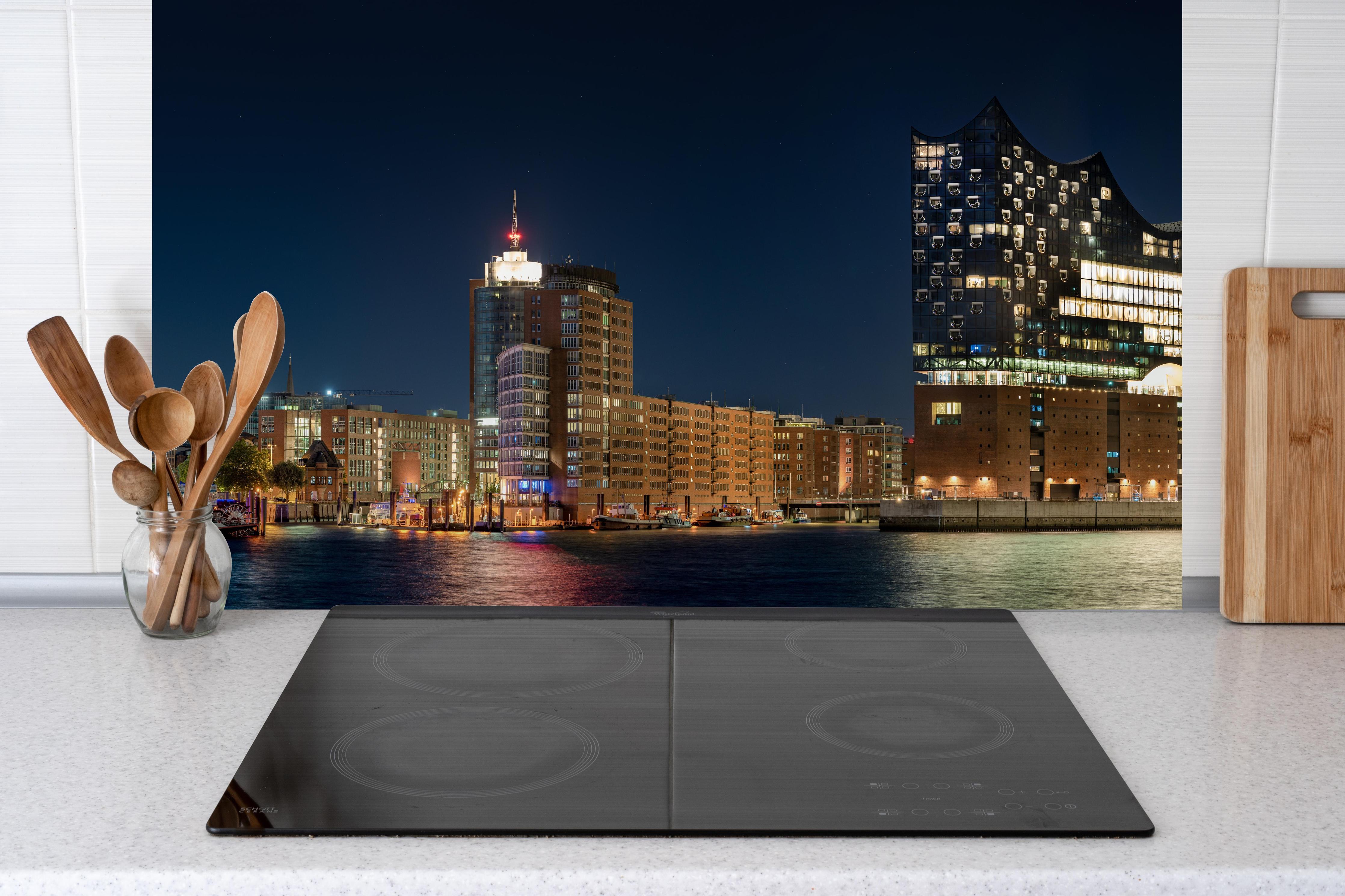 Küche - Hamburg bei Nacht hinter Cerankochfeld und Holz-Kochutensilien