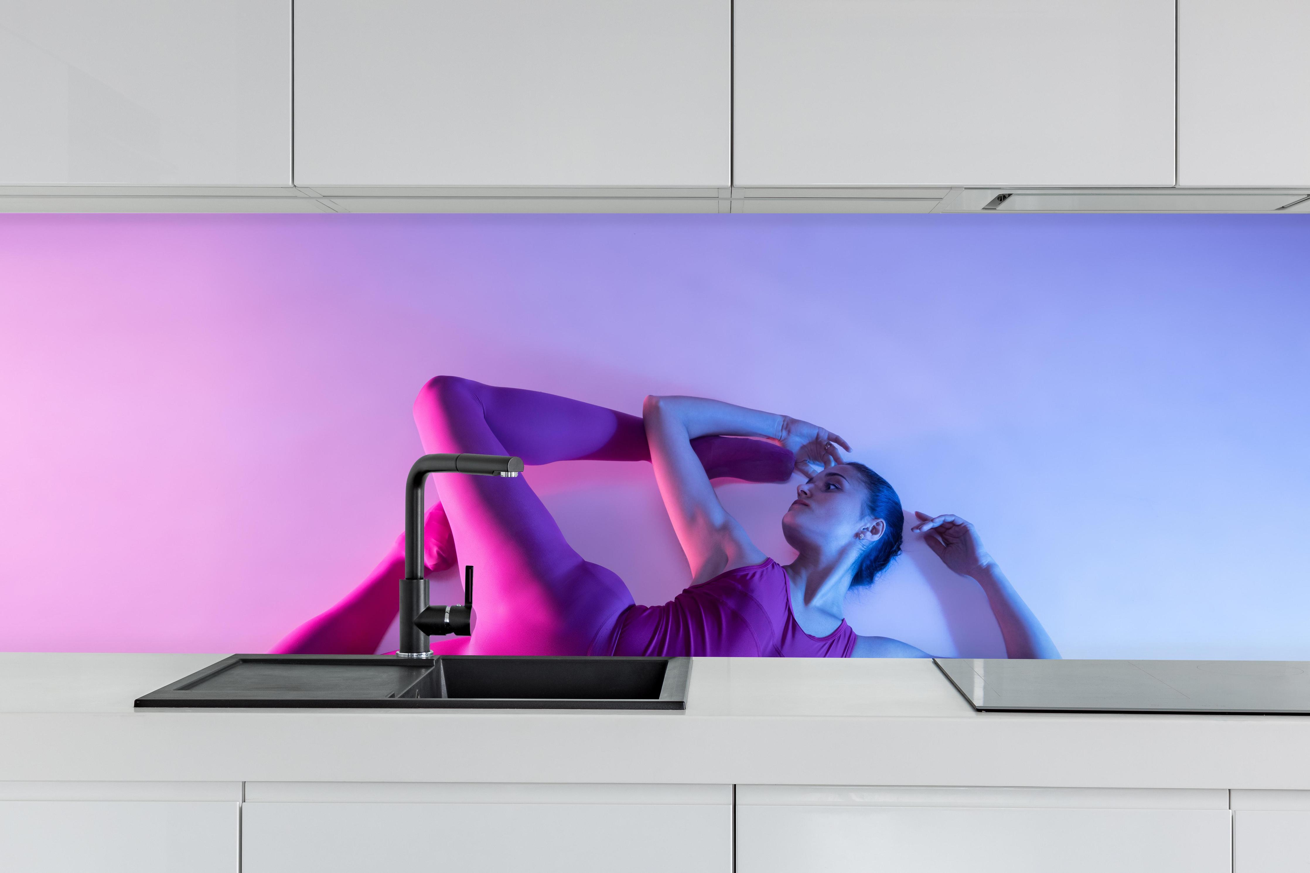 Küche - Junge Balletttänzerin hinter weißen Hochglanz-Küchenregalen und schwarzem Wasserhahn