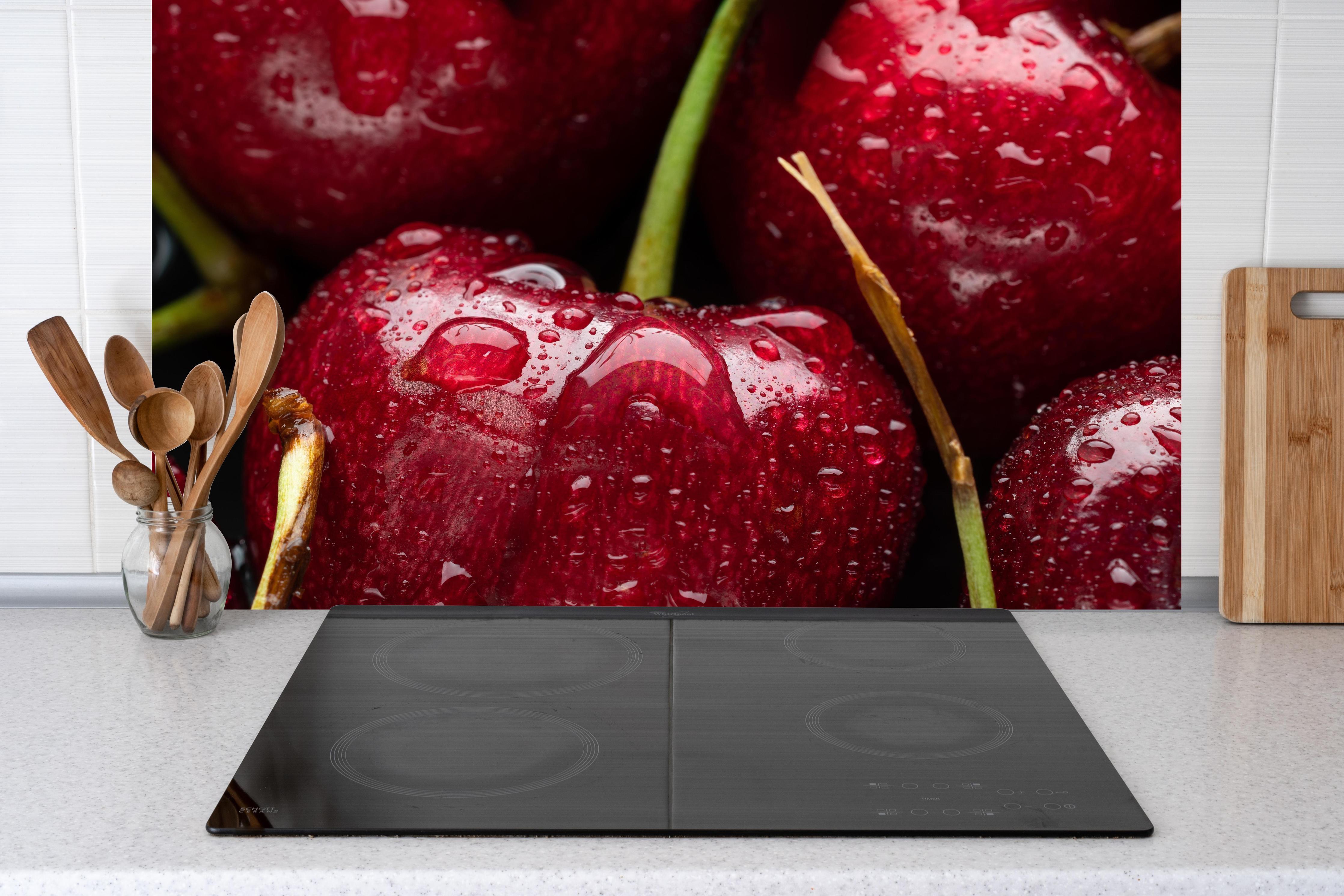 Küche - Kirschen mit Wasserperlen hinter Cerankochfeld und Holz-Kochutensilien