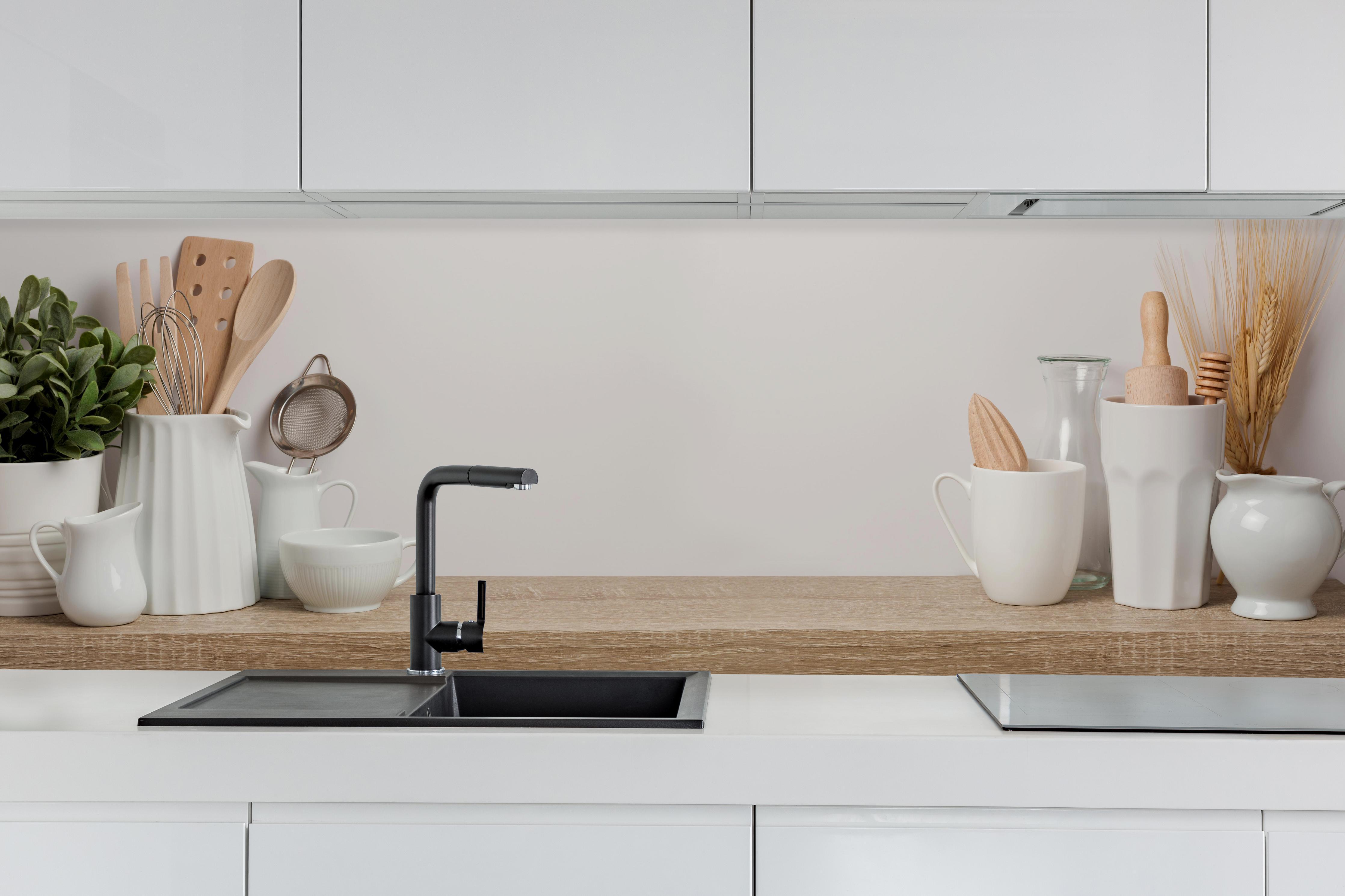 Küche - Küchenutensilien & Geschirr hinter weißen Hochglanz-Küchenregalen und schwarzem Wasserhahn