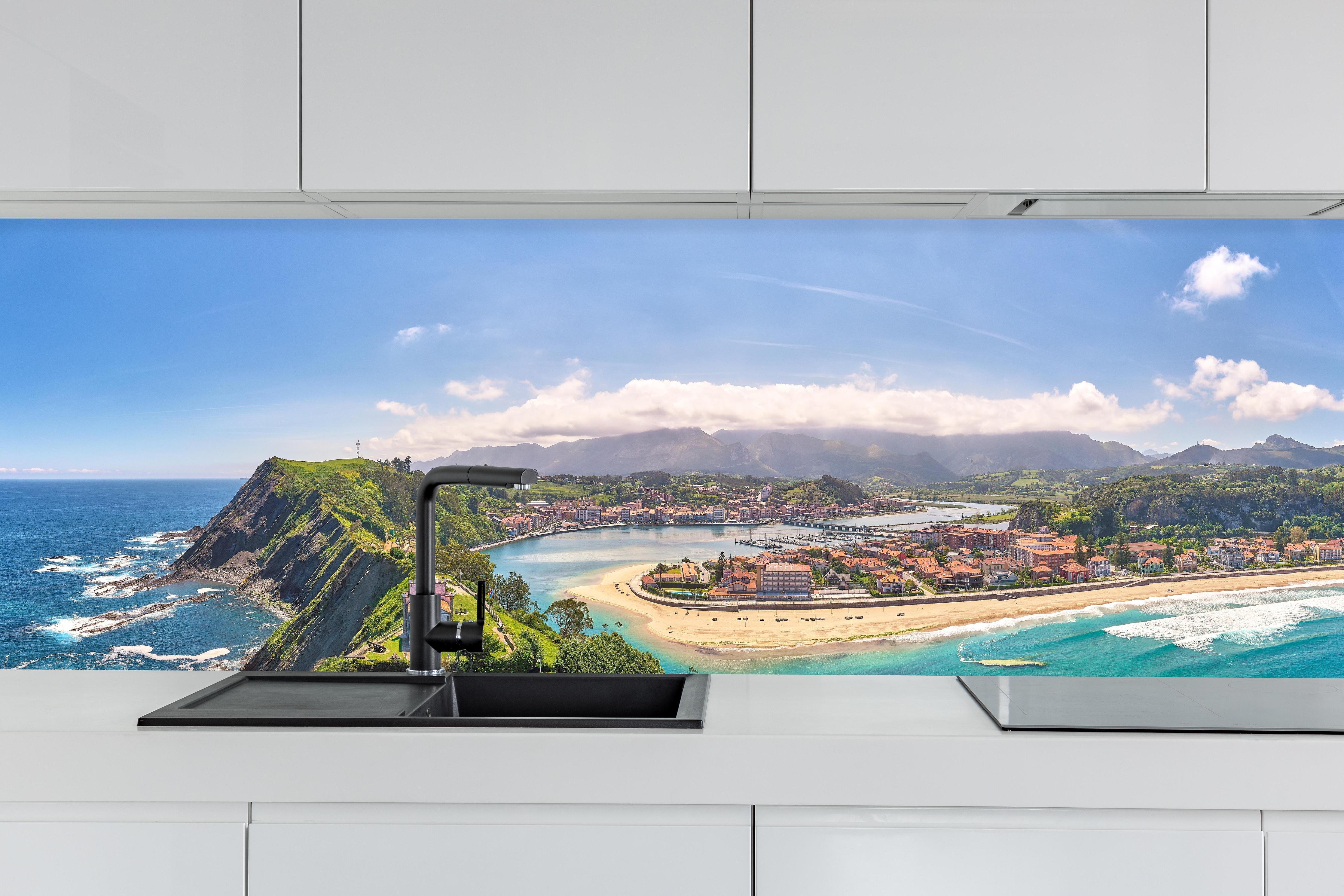 Küche - Luftaufnahme Ribadesella-Kirche - Spanien hinter weißen Hochglanz-Küchenregalen und schwarzem Wasserhahn