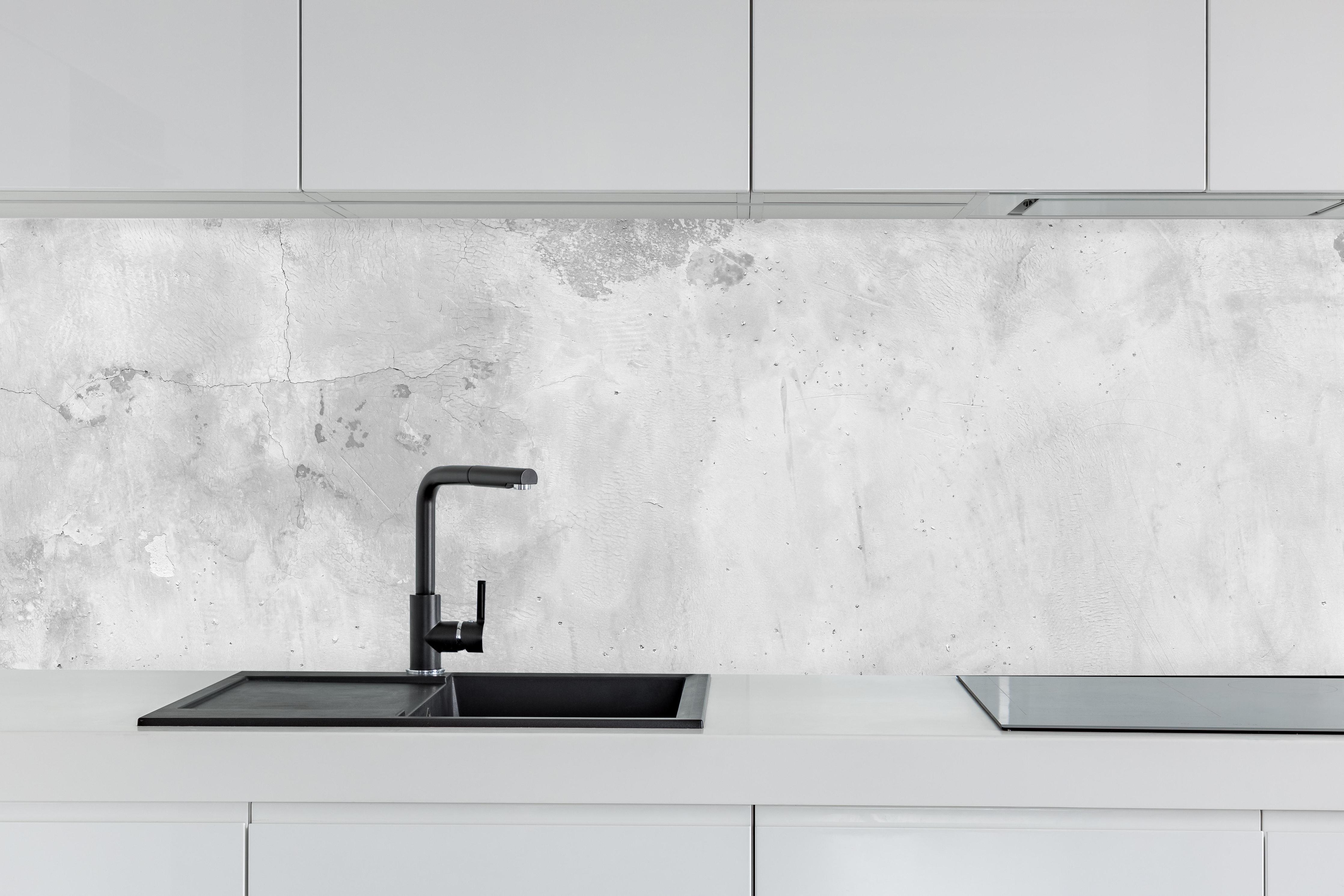 Küche - Panorama einer alten Betonwand hinter weißen Hochglanz-Küchenregalen und schwarzem Wasserhahn