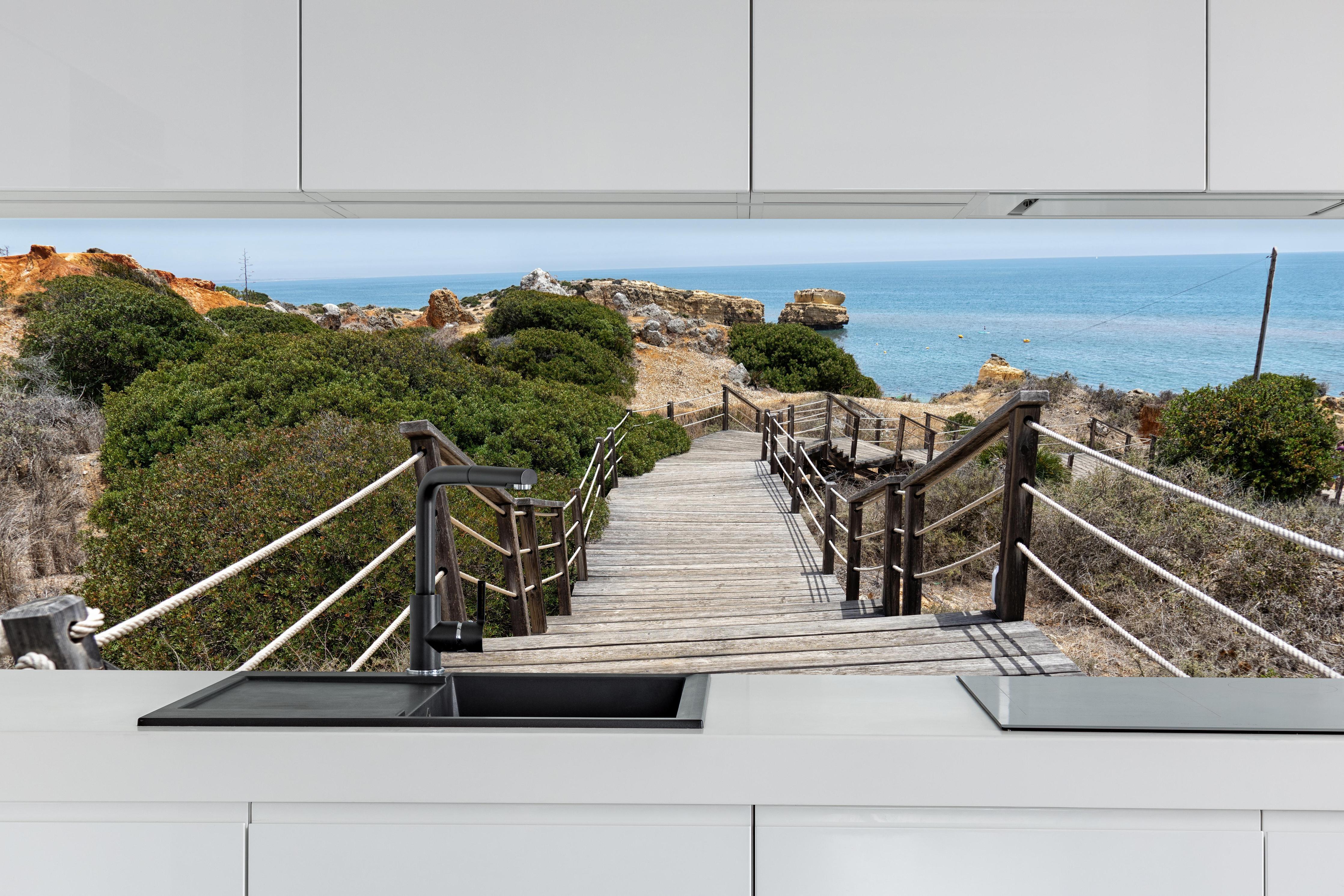 Küche - Portugal Küstenlinie hinter weißen Hochglanz-Küchenregalen und schwarzem Wasserhahn