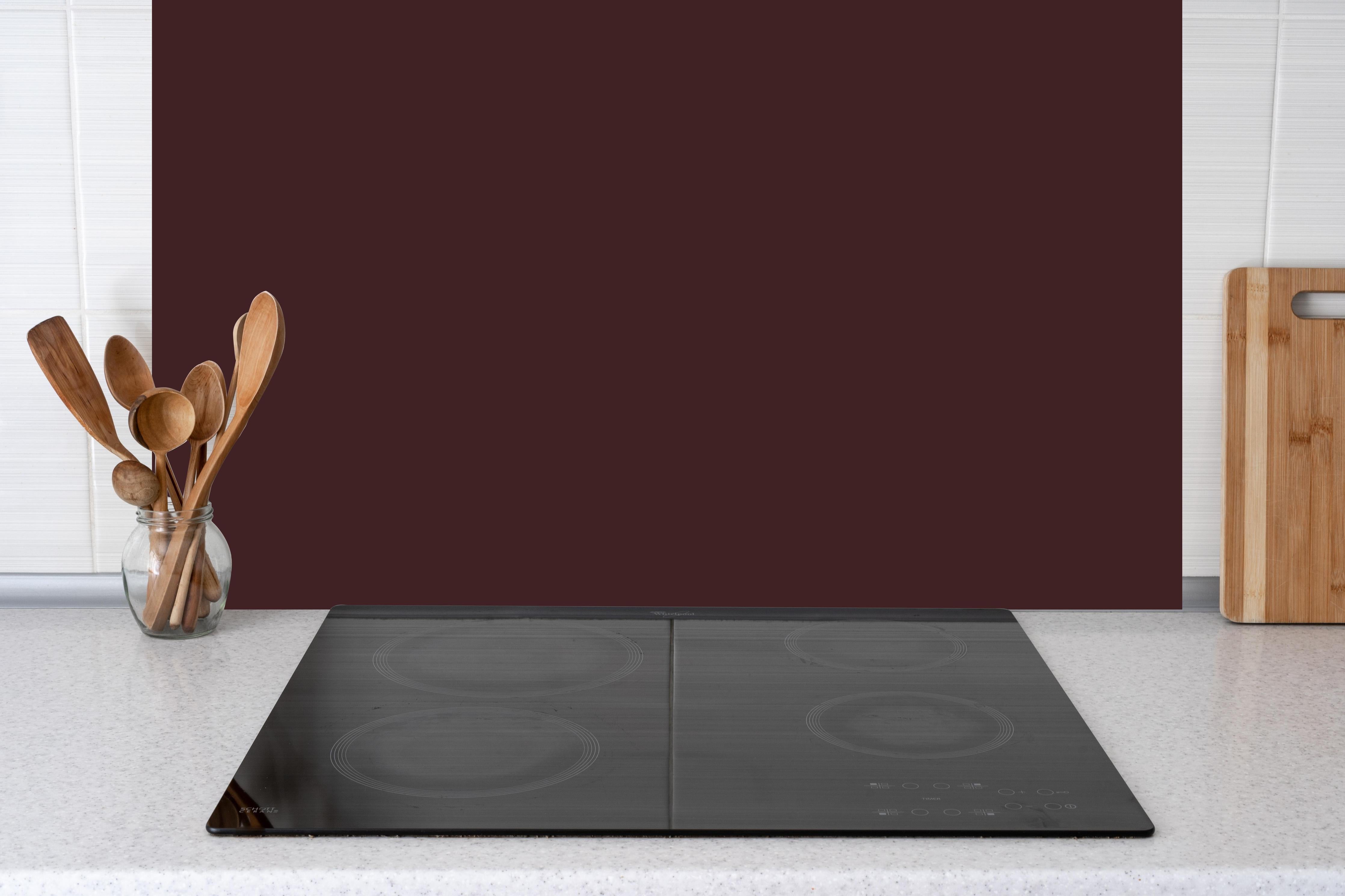 Küche - RAL 3007 (Schwarzrot) hinter Cerankochfeld und Holz-Kochutensilien