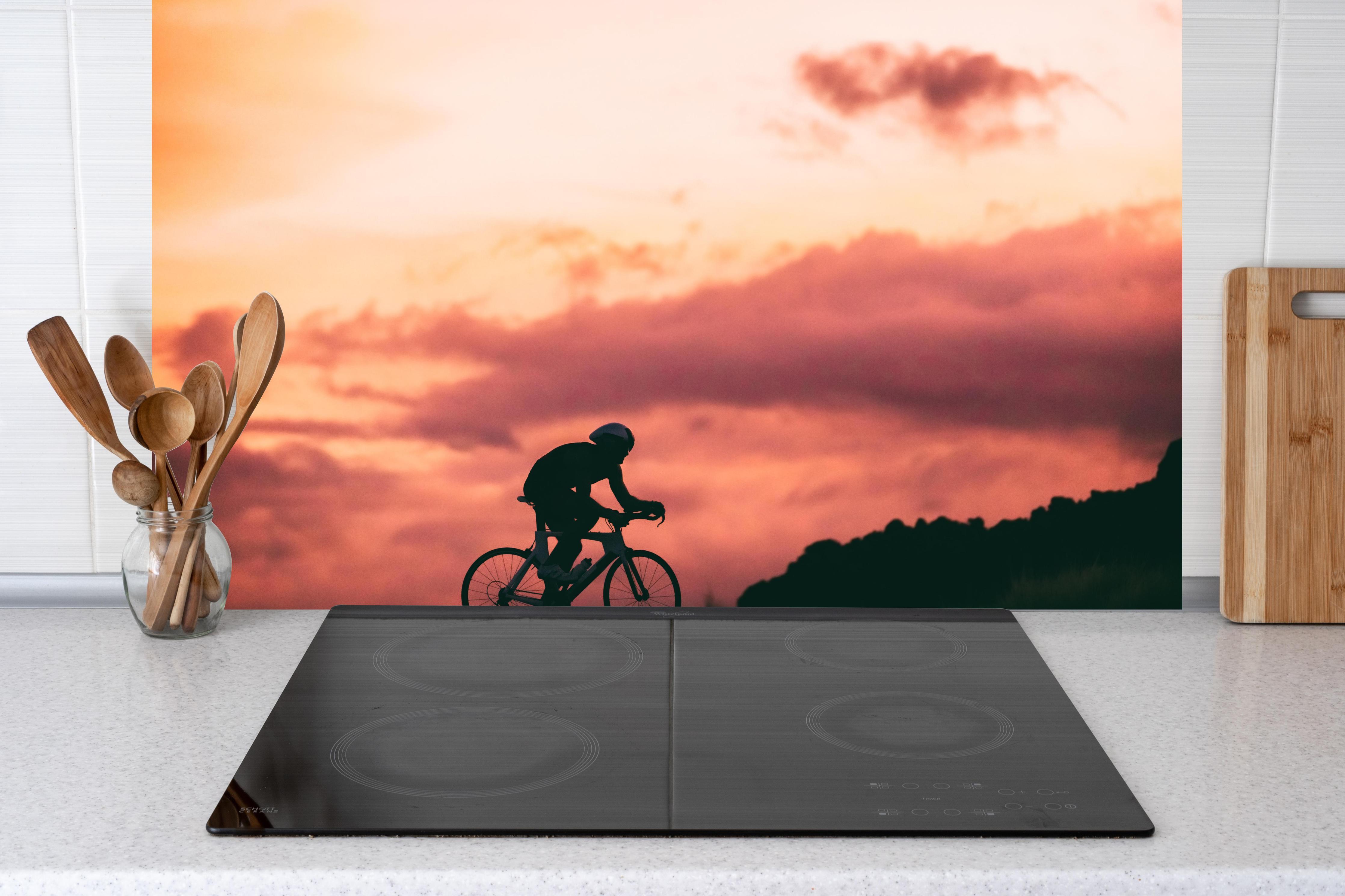 Küche - Rennradfahrer hinter Cerankochfeld und Holz-Kochutensilien