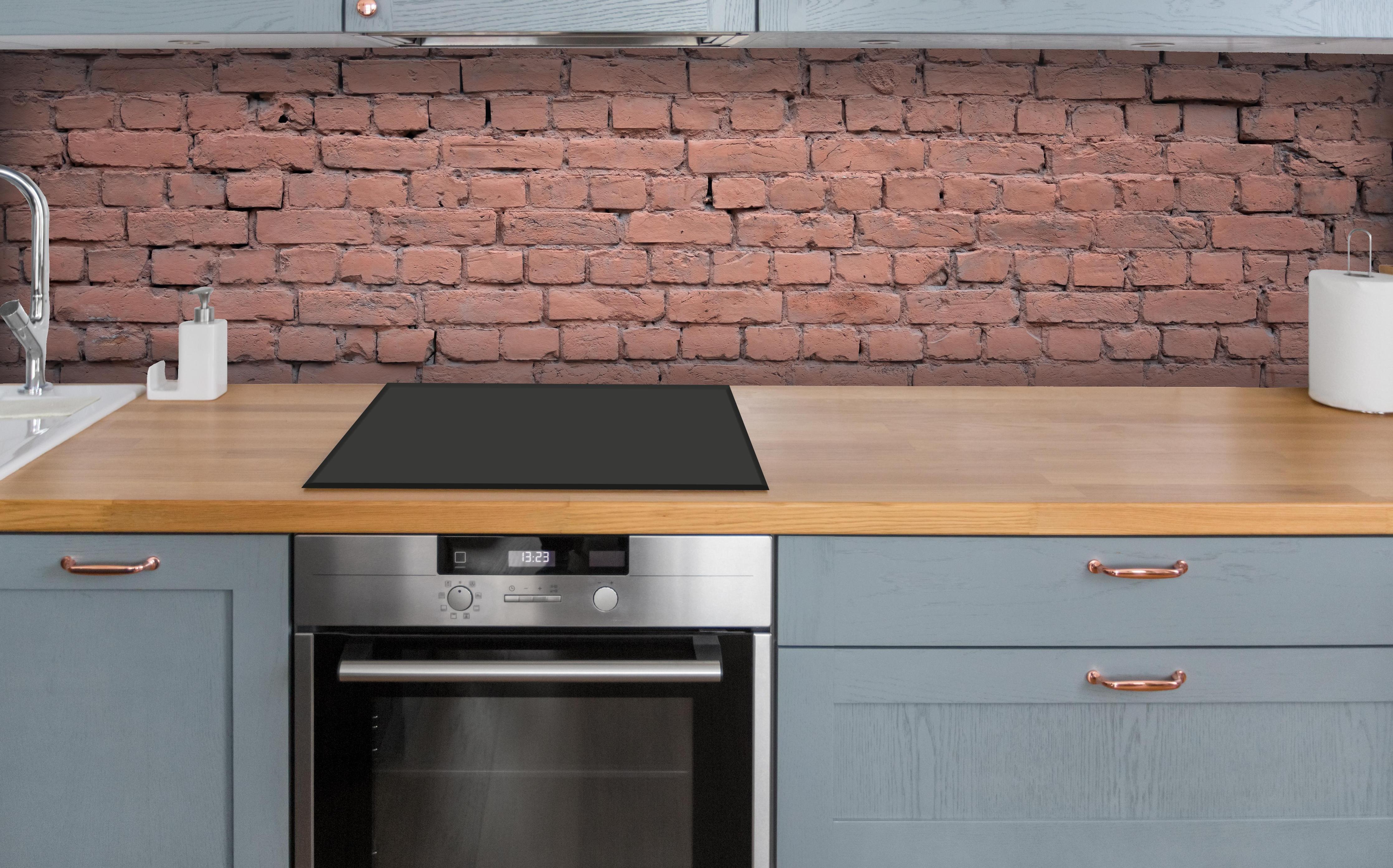 Küche - Rosafarbige Ziegelwandoberfläche über polierter Holzarbeitsplatte mit Cerankochfeld