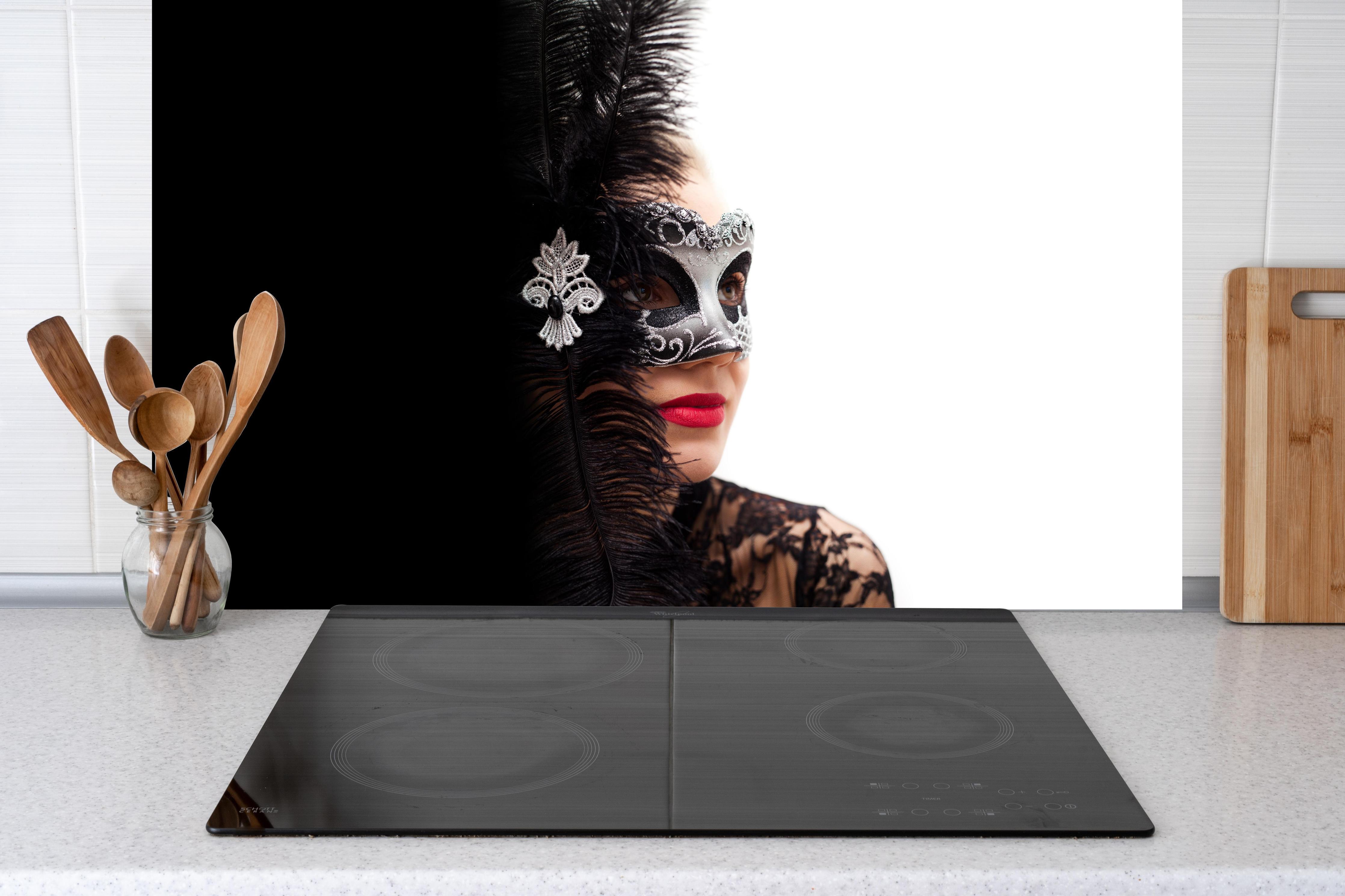 Küche - Schwarzer Schwan Frau mit Maske hinter Cerankochfeld und Holz-Kochutensilien