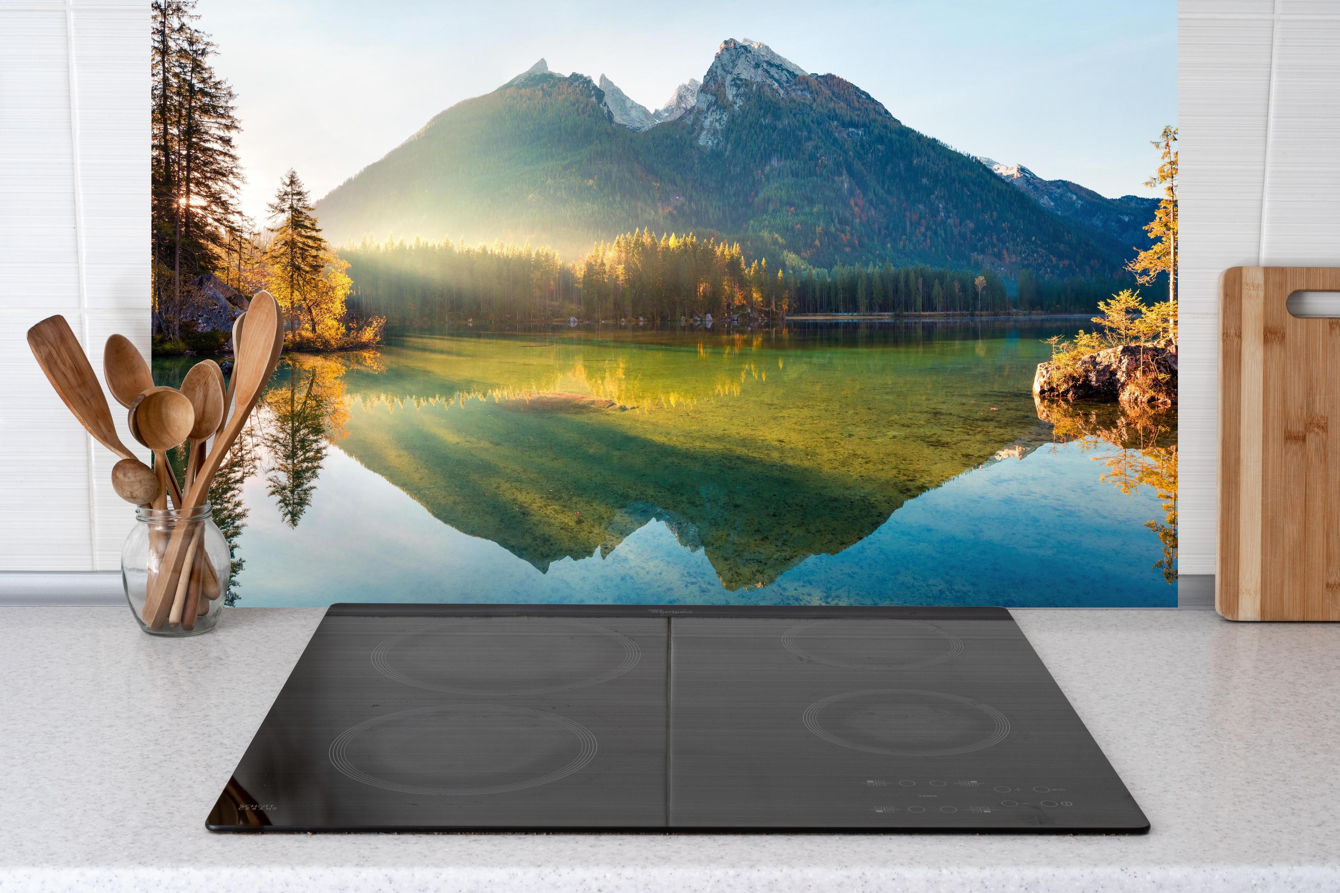 Küche - Sonnenaufgang am Hintersee hinter Cerankochfeld und Holz-Kochutensilien