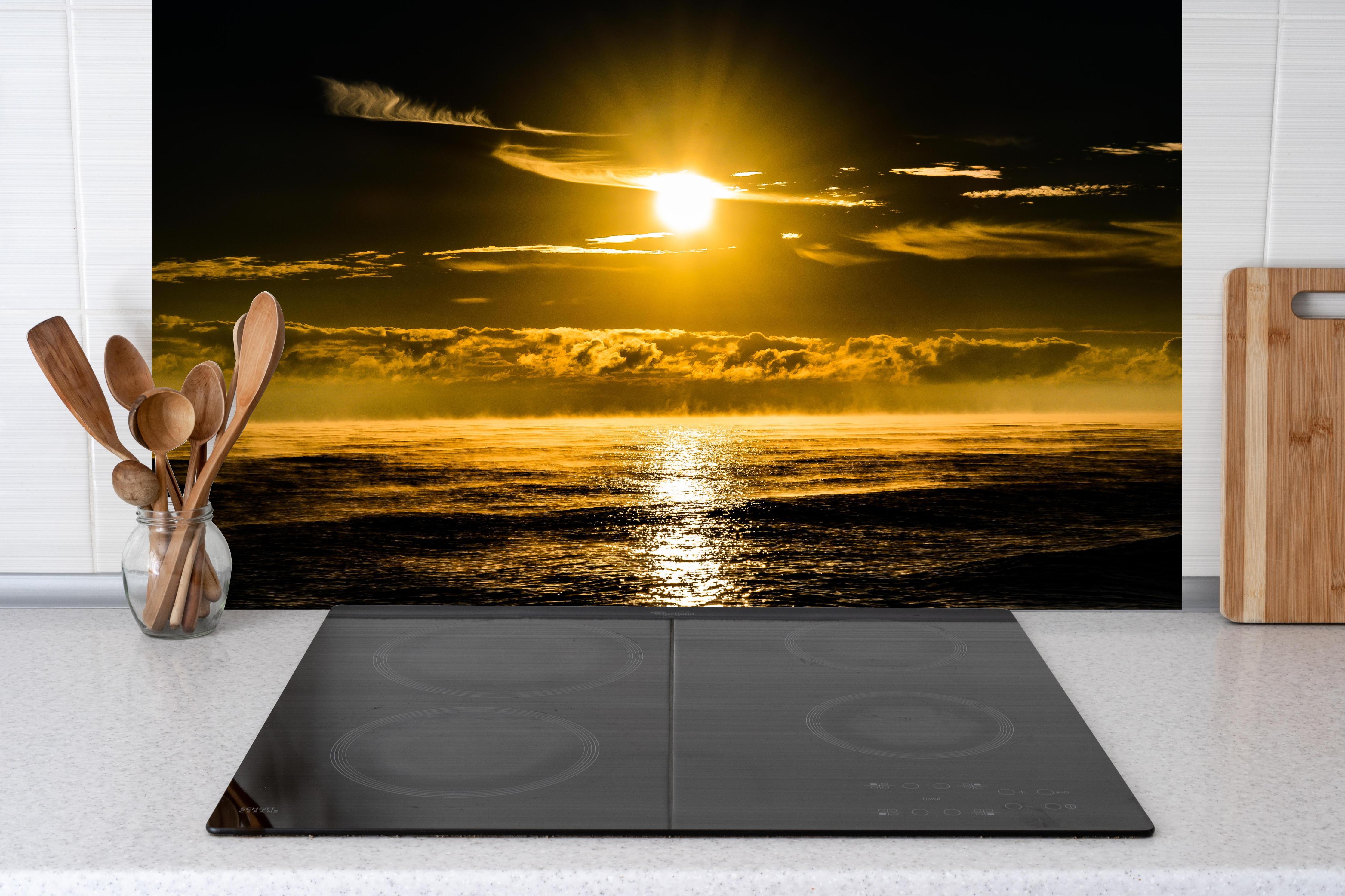 Küche - Sonnenuntergang über dem Meer hinter Cerankochfeld und Holz-Kochutensilien