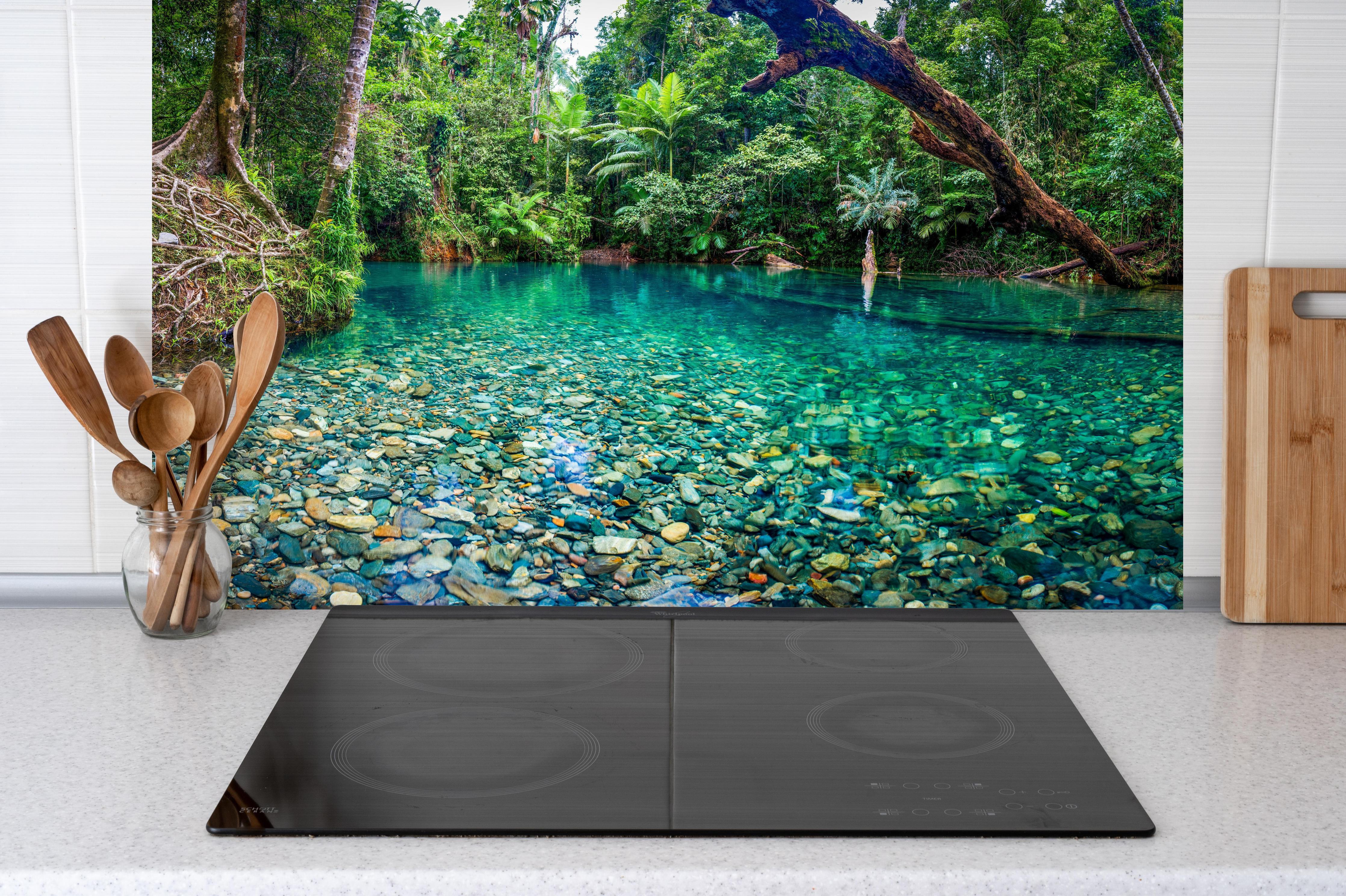 Küche - Tropischer Bach mit klarem Wasser hinter Cerankochfeld und Holz-Kochutensilien